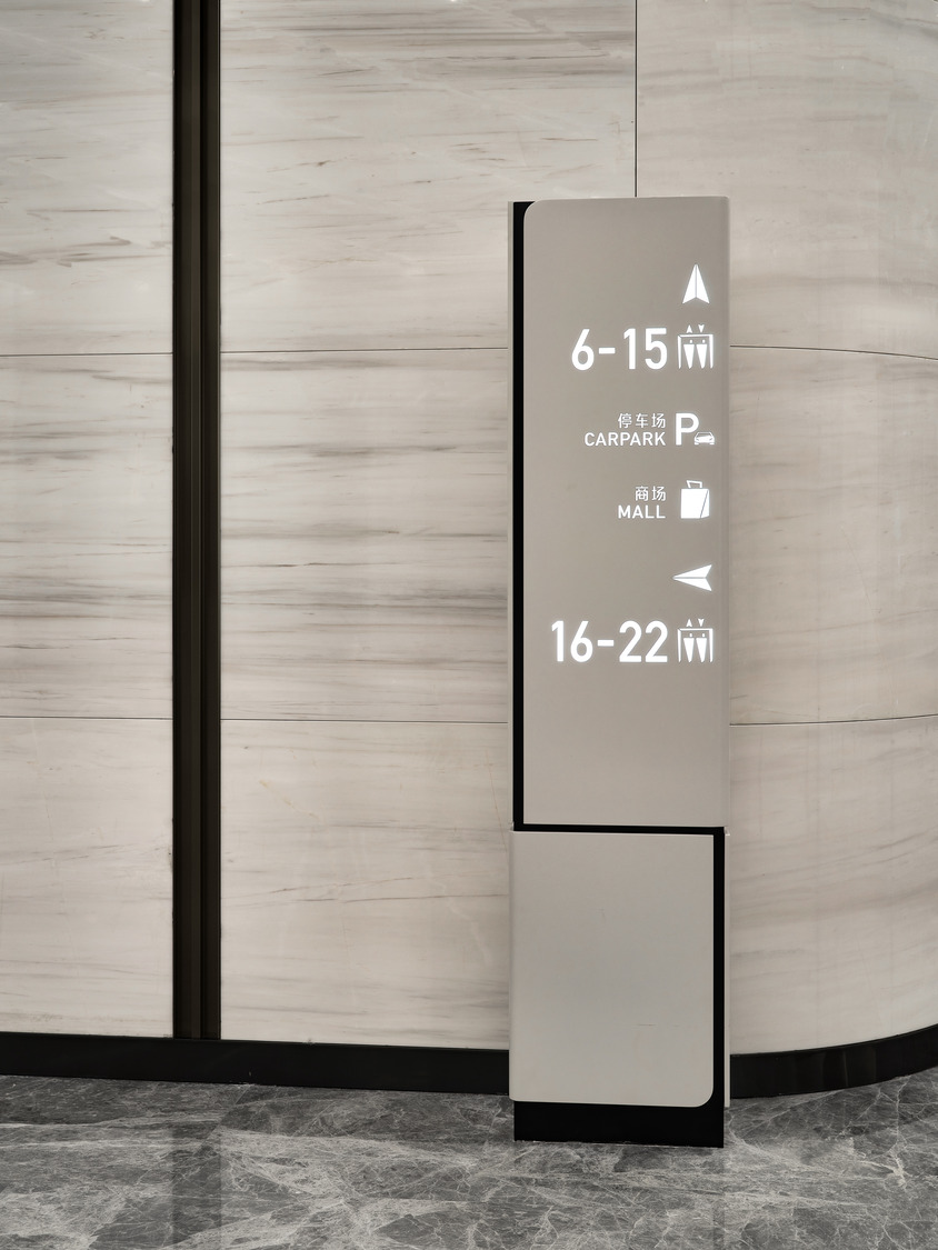 Spacious modern office lobby with geometric ceiling patterns, sleek marble floors, and a minimalist reception desk, conveying a sophisticated and elegant tone.
