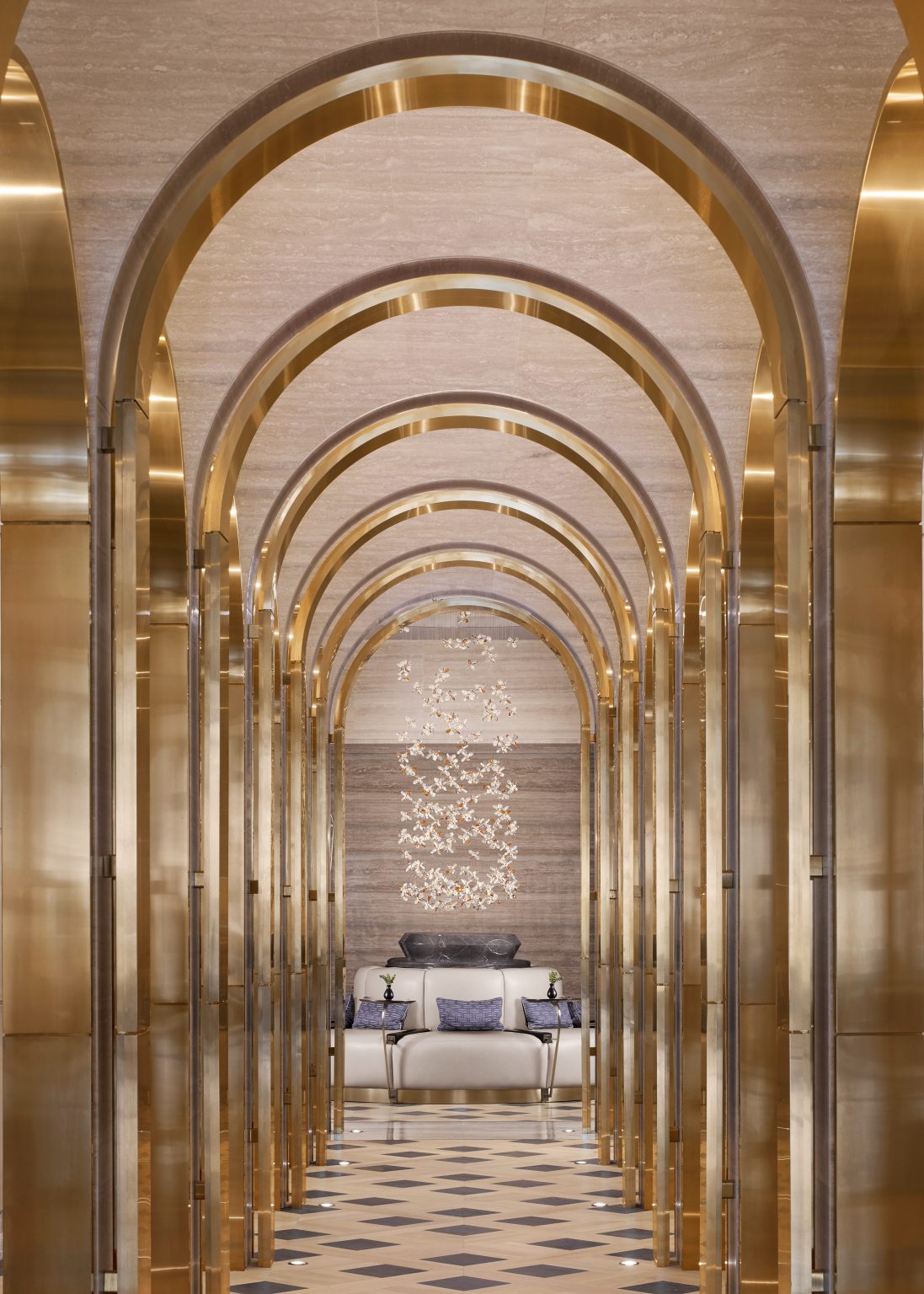 Luxurious resort spa interior with arched golden doorways and marble walls. A person in a white robe walks through the opulent, serene hallway.