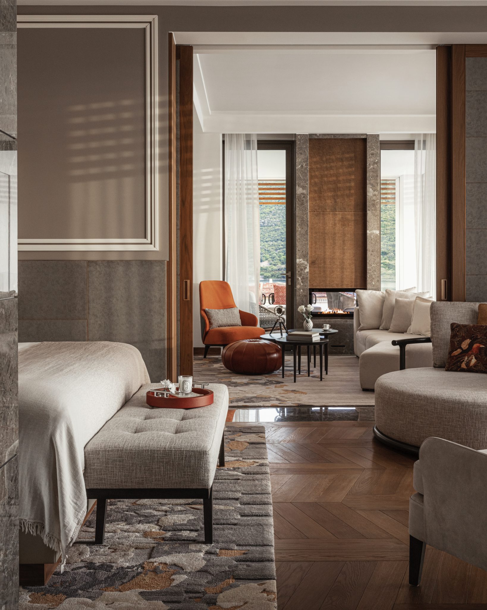 Luxurious hotel room with a king-sized bed, elegant decor, and large windows offering a stunning city view. Pastel tones and plush seating create a cozy, sophisticated ambiance.