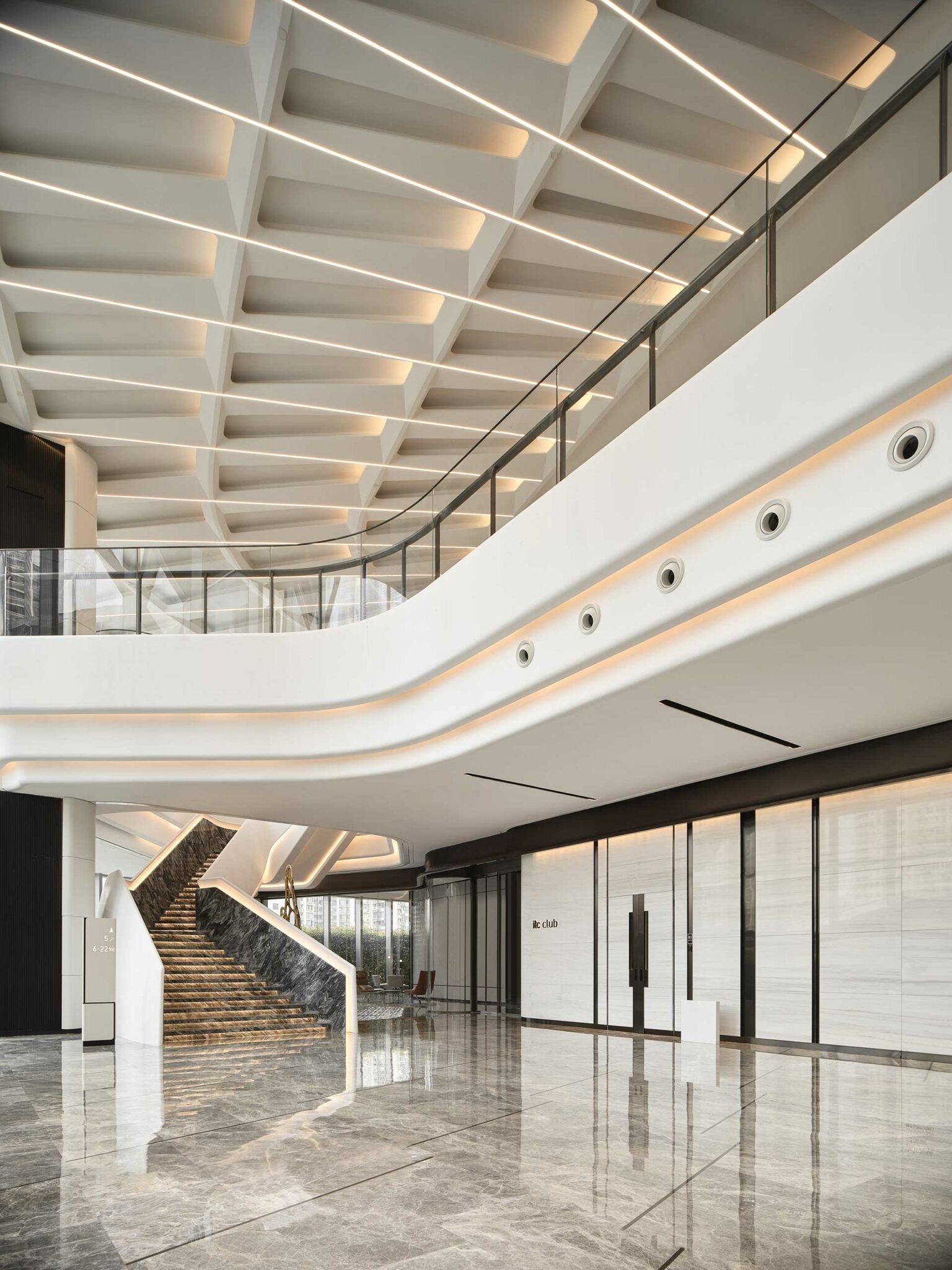 Modern, spacious office lobby with sleek marble floors and a grand staircase. Geometric ceiling and soft lighting create a minimalist, elegant atmosphere.