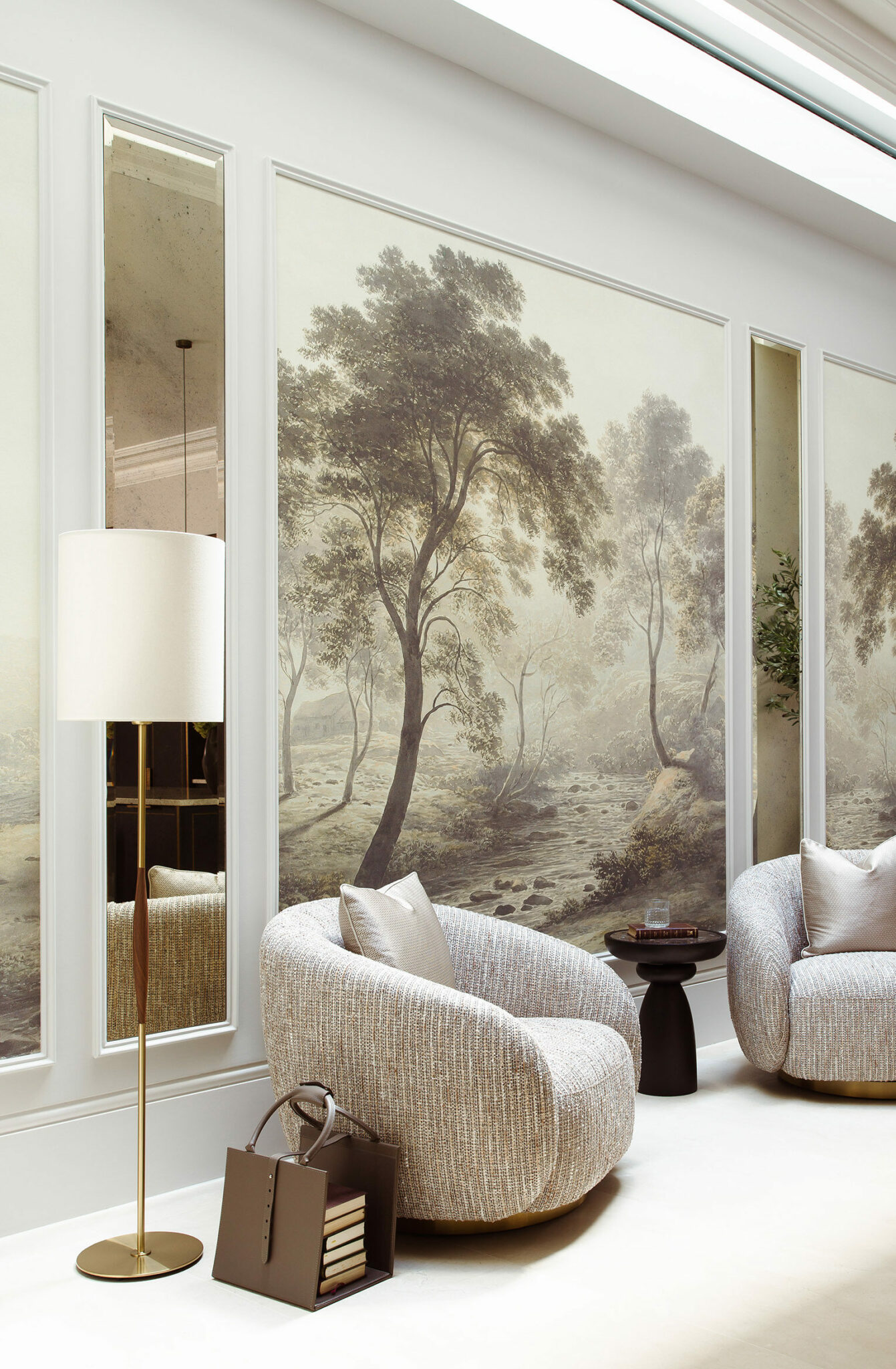 Luxurious lounge with two textured armchairs, a floor lamp, and a soft landscape mural depicting trees and a stream. Cozy, elegant ambiance.