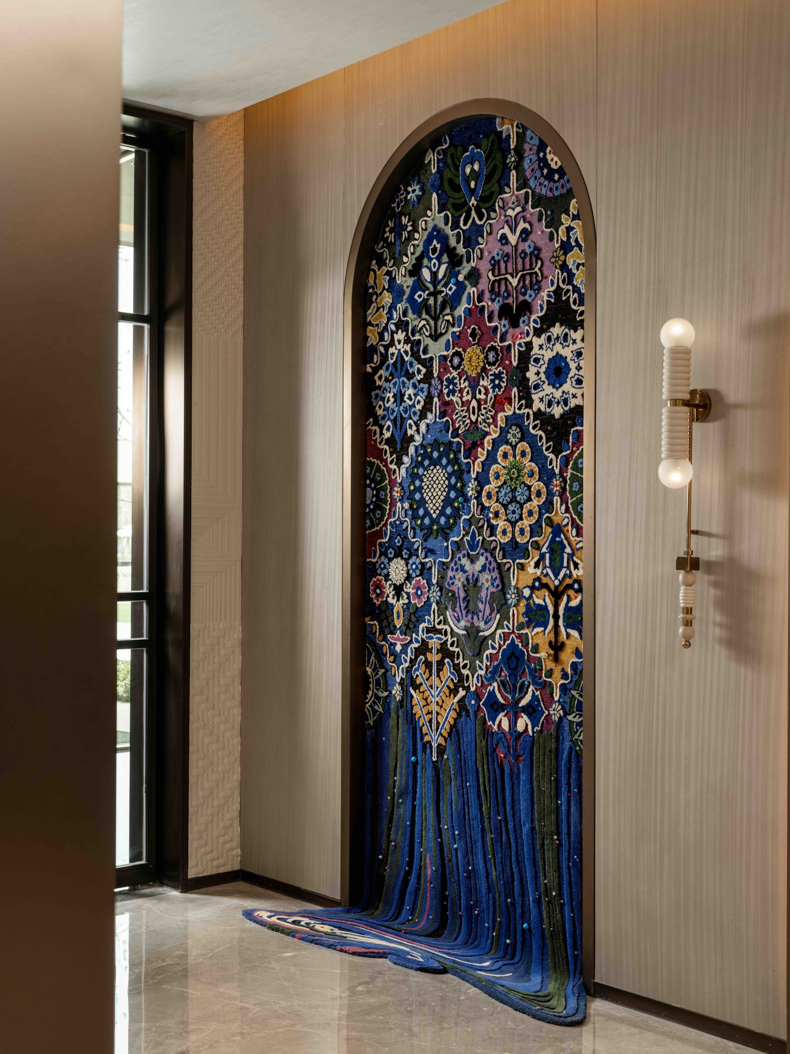 Decorative arched tapestry installation with vibrant blue and multicolored patterns cascading onto the floor.