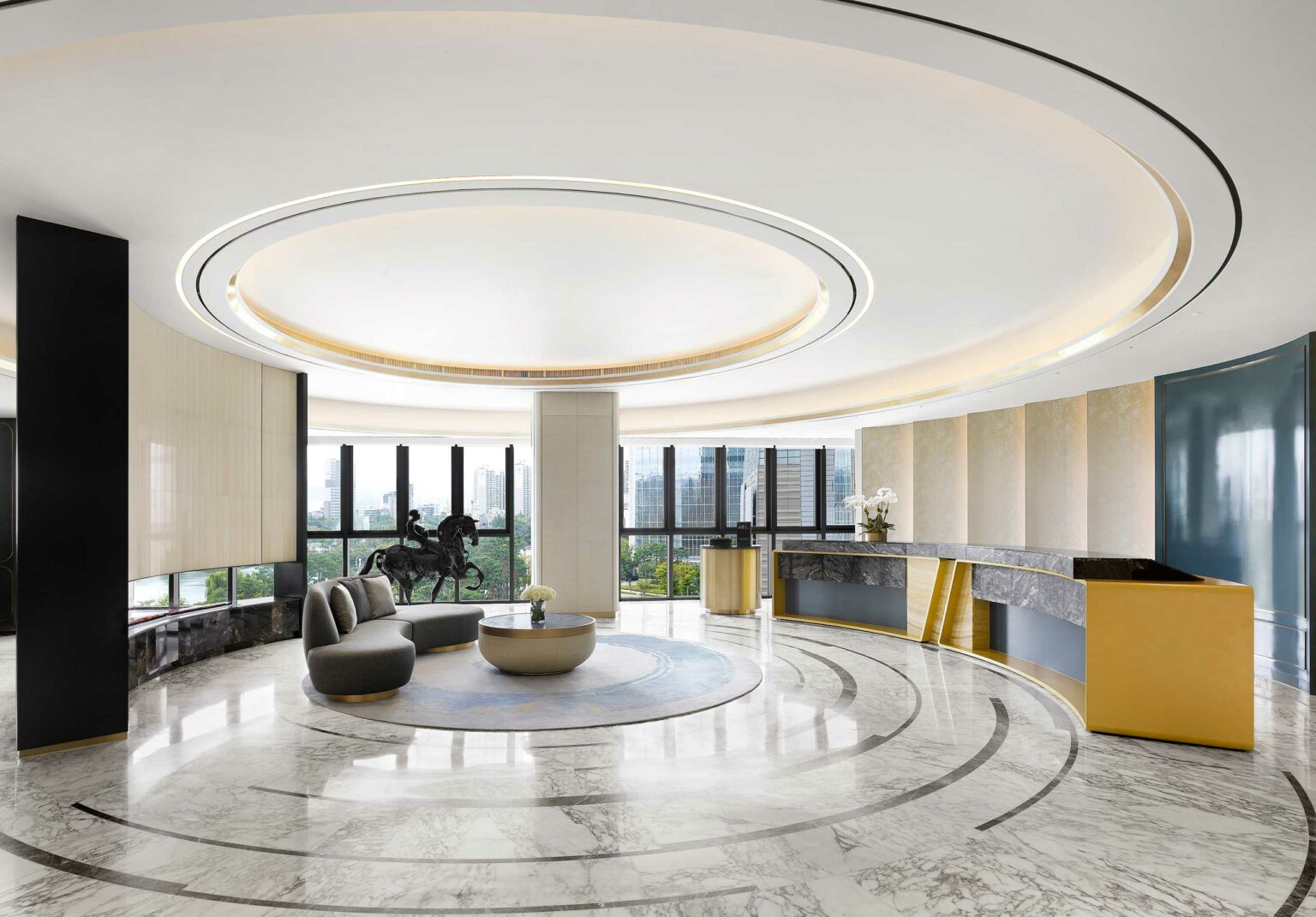 Sophisticated hotel lobby with a circular ceiling design, modern seating, and a horse statue. Large windows reveal a cityscape, evoking elegance and grandeur.