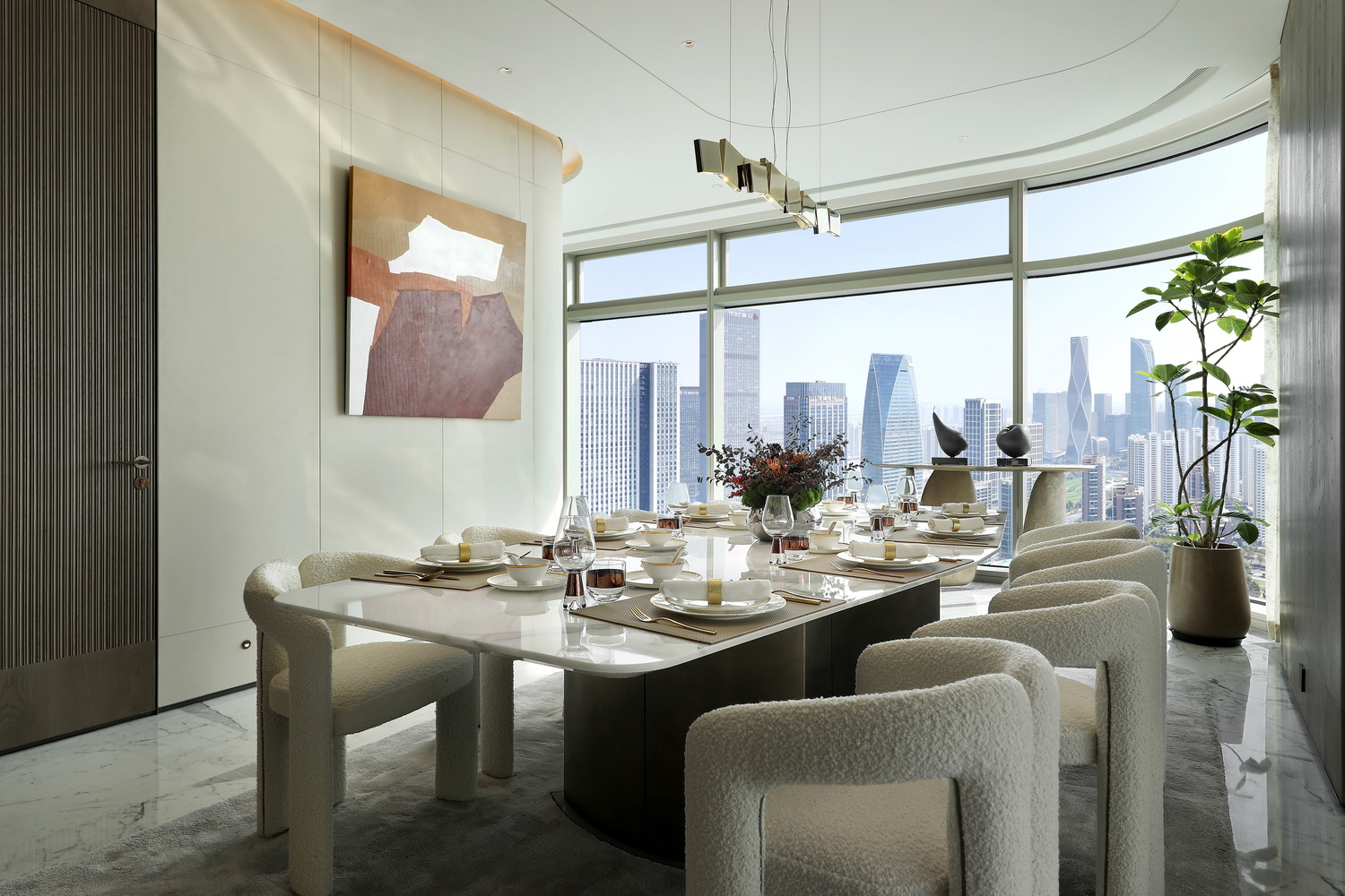A modern living room with large windows, sunlight streaming in. Features include a plush chair, abstract wall art, round table, and curved sofa. The ambiance is serene and sophisticated.