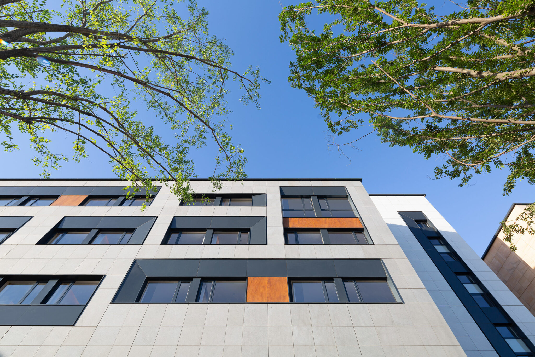 Facade of Unique Henan Theatre Hotel China featuring a modern building exterior with large reflective glass windows and small balconies on a black and beige facade. Geometric lines create a sleek, urban look.