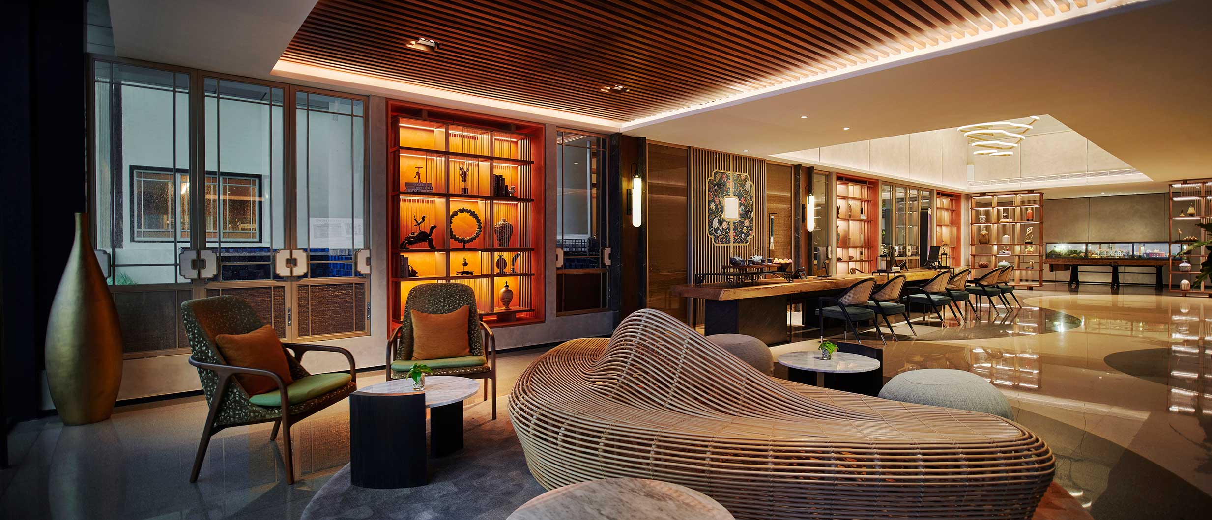 Luxurious modern hotel lobby with wood accents, featuring a curvy wicker sofa, artistic shelves, elegant lighting, and cozy seating, exuding warmth and sophistication.