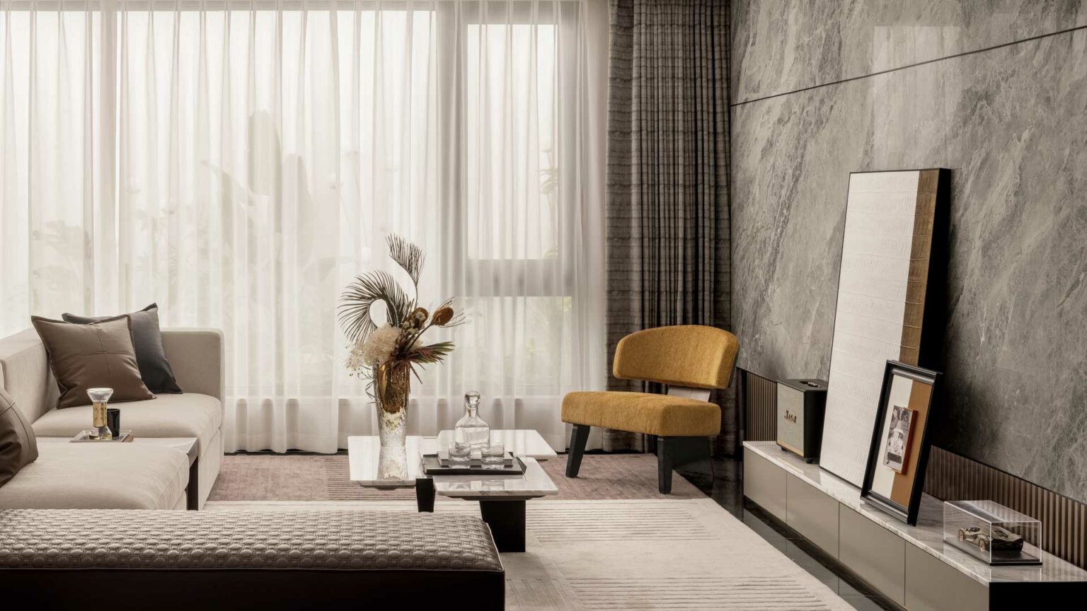 A modern, elegant living room with a beige sofa, mustard chair, marble coffee table, dried floral arrangement, and large window with sheer curtains. Warm and inviting.