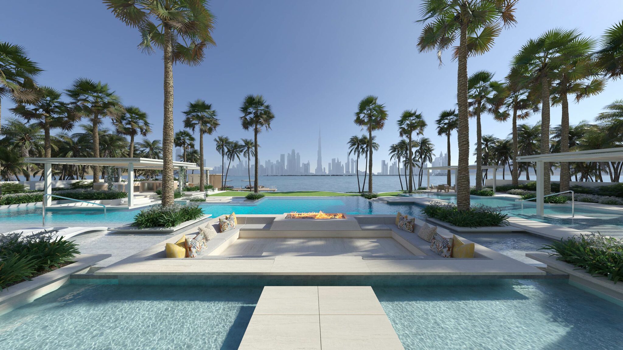 Luxurious poolside lounge with palm trees, overlooking a tranquil sea and a Dubai's cityscape. Sunny ambiance and inviting seating around a central fire pit.