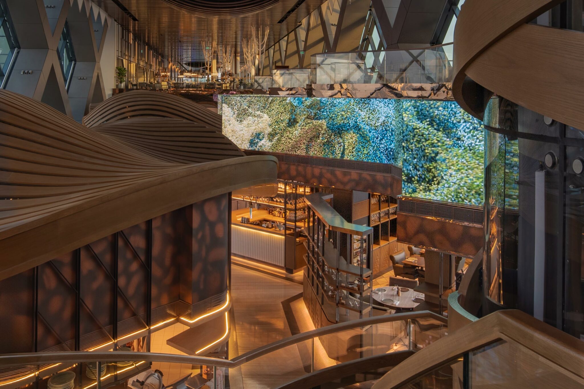 Futuristic interior with curved wooden structures, warm lighting, and digital screens displaying abstract nature images. Luxurious and modern ambiance.