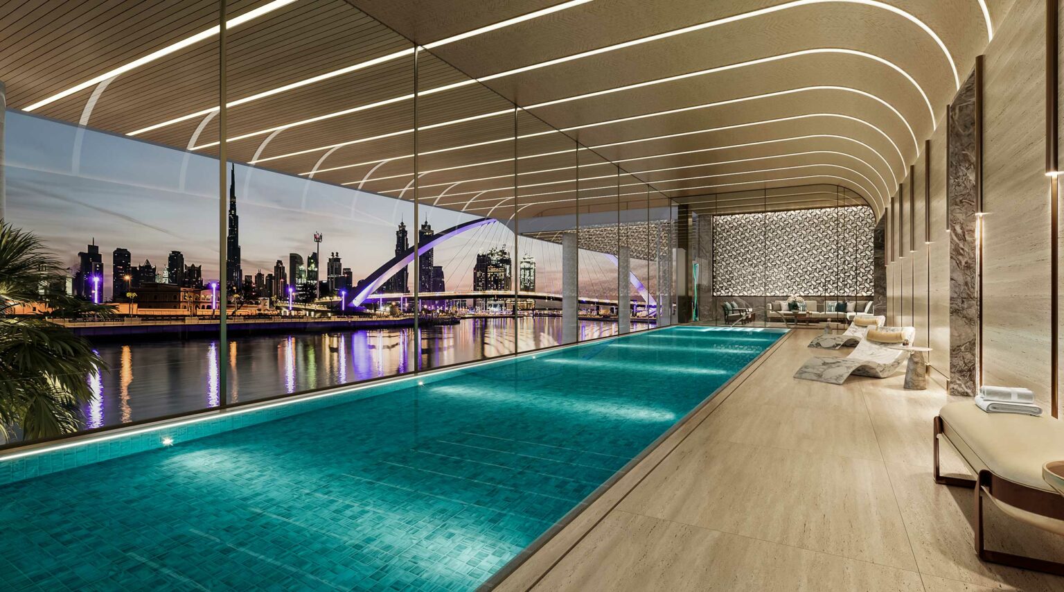 Luxurious indoor pool area with sleek design, overlooking Dubai's skyline at dusk. Spacious lounge chairs line the right, creating an elegant, serene ambiance.
