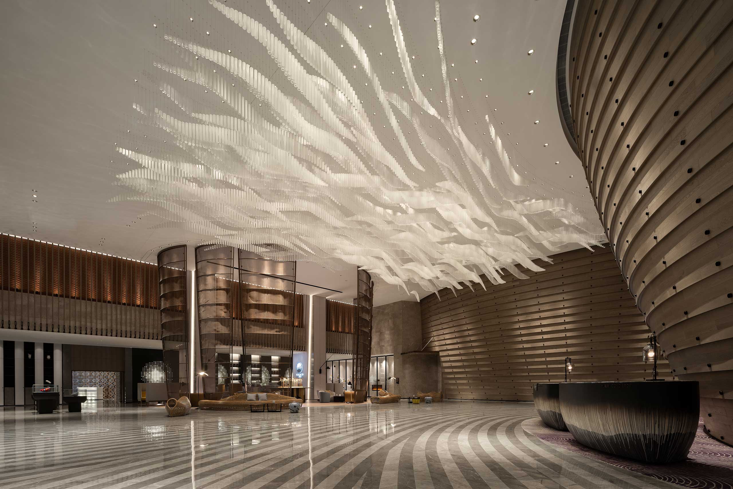 Luxurious hotel lobby with a grand, wave-like ceiling design. Curved wood textures, modern seating, and warm lighting create an elegant atmosphere.