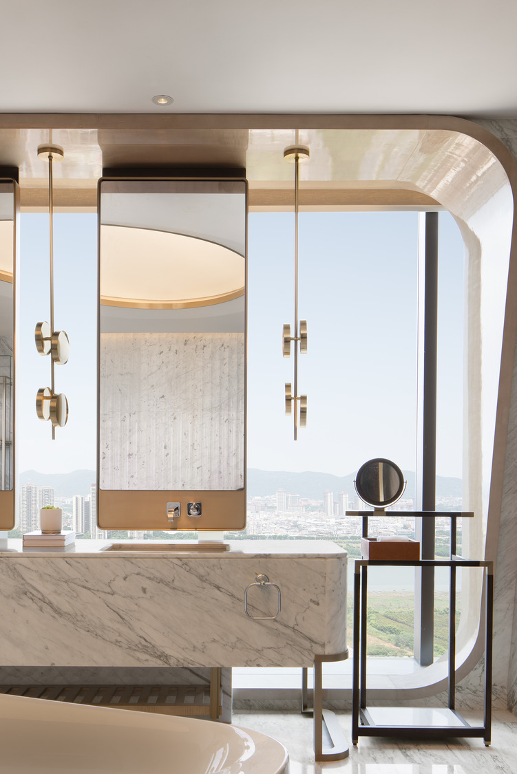 A modern bathroom with a sleek marble vanity, stylish mirrors, and elegant lighting, offering a stunning view through large windows, creating a luxurious and serene atmosphere.