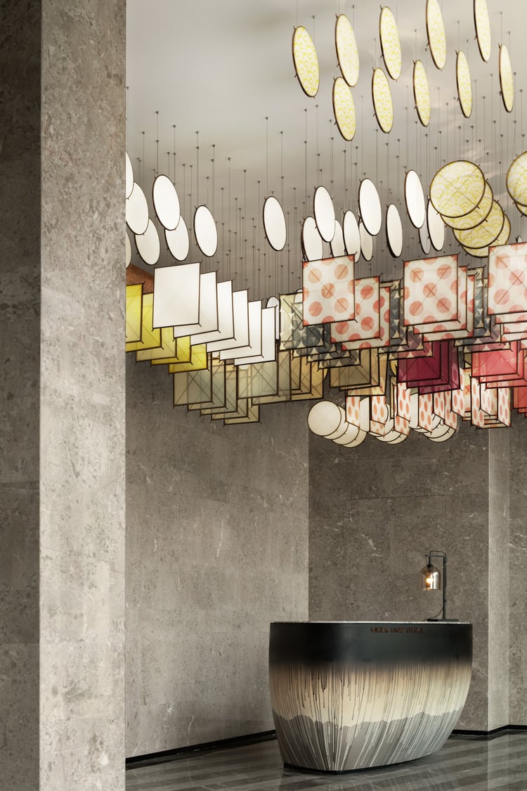 A vibrant hotel check in area featuring an artistic display of colorful hanging lanterns above a sleek, circular reception desk, creating a lively and welcoming atmosphere for guests.