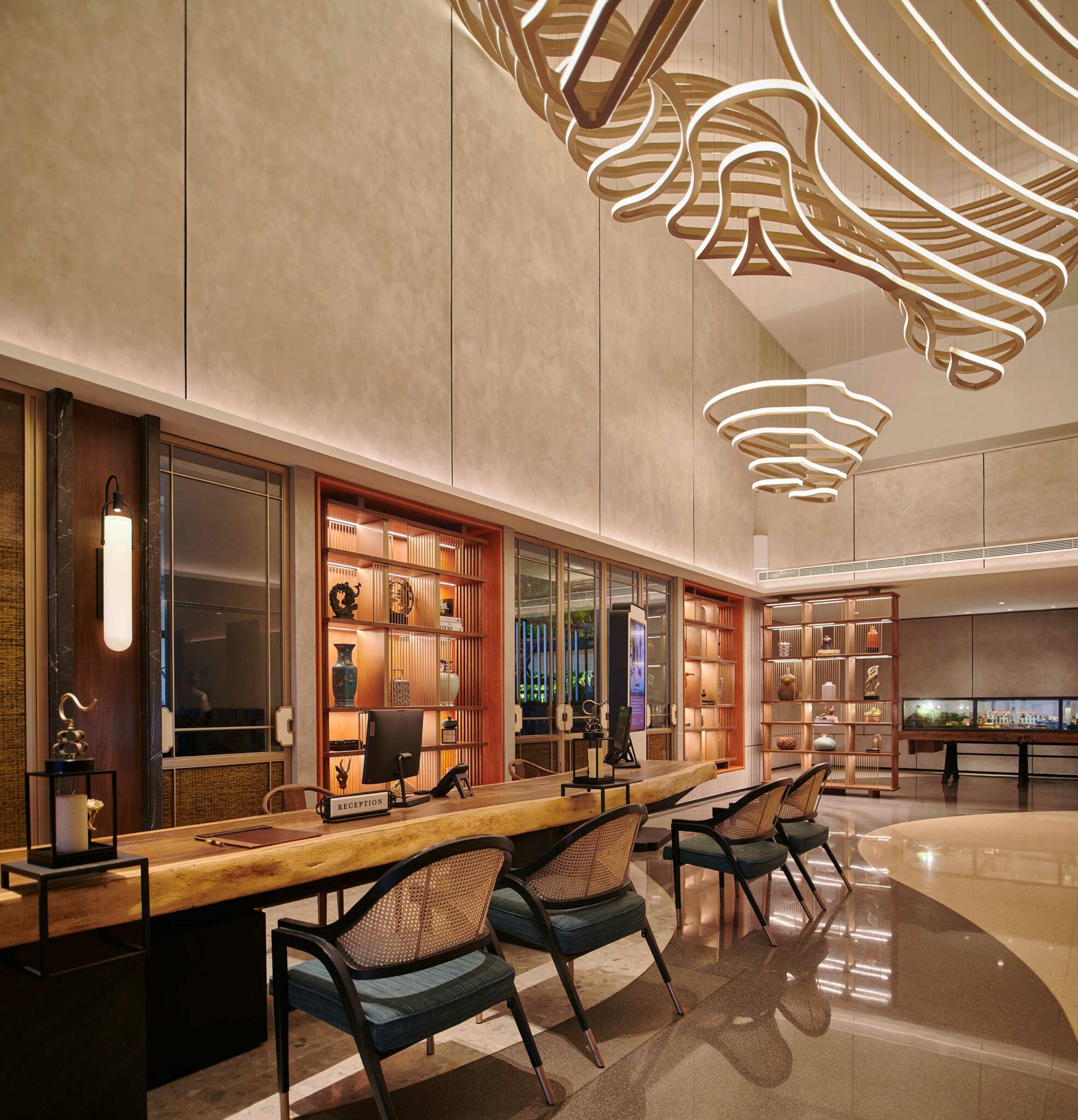 Luxurious hotel reception area with elegant wood and fabric chairs, a sleek wooden desk, and illuminated decorative shelves, exuding a warm, inviting ambiance.