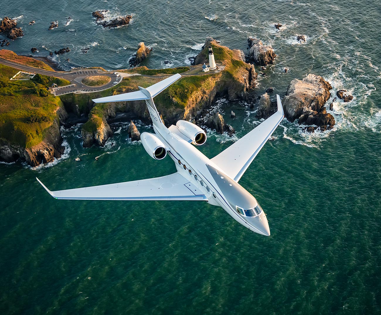 A private jet soaring above a rocky coastline features a small island with a lighthouse. The ocean's vivid blue waves crash against the rugged cliffs.