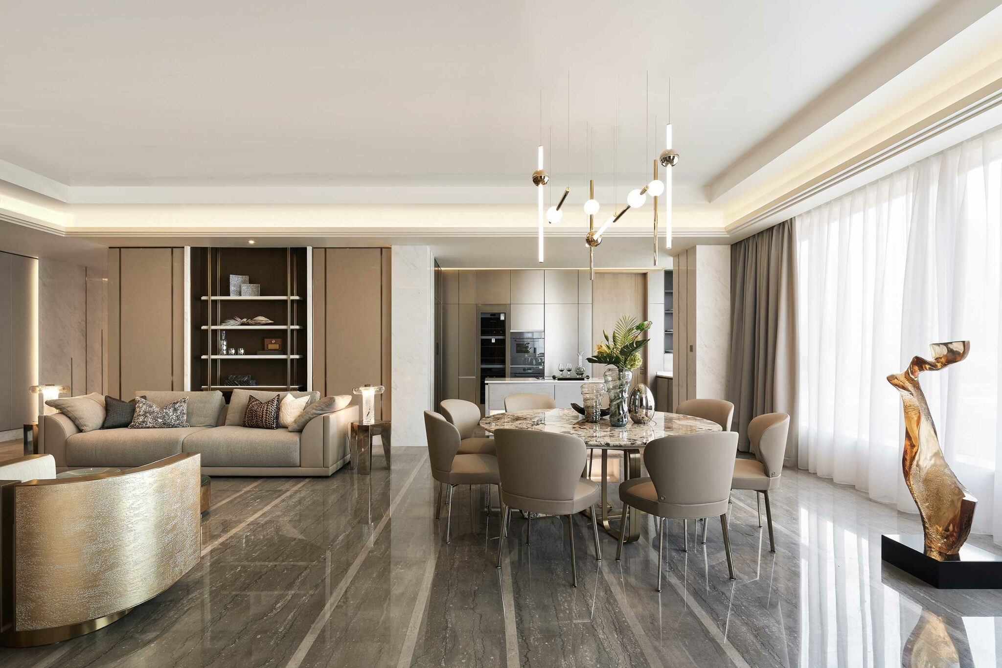 Modern living and dining area with a neutral palette. Features a beige sofa, round dining table with eight chairs, and elegant lighting. Sunlight filters through sheer curtains.