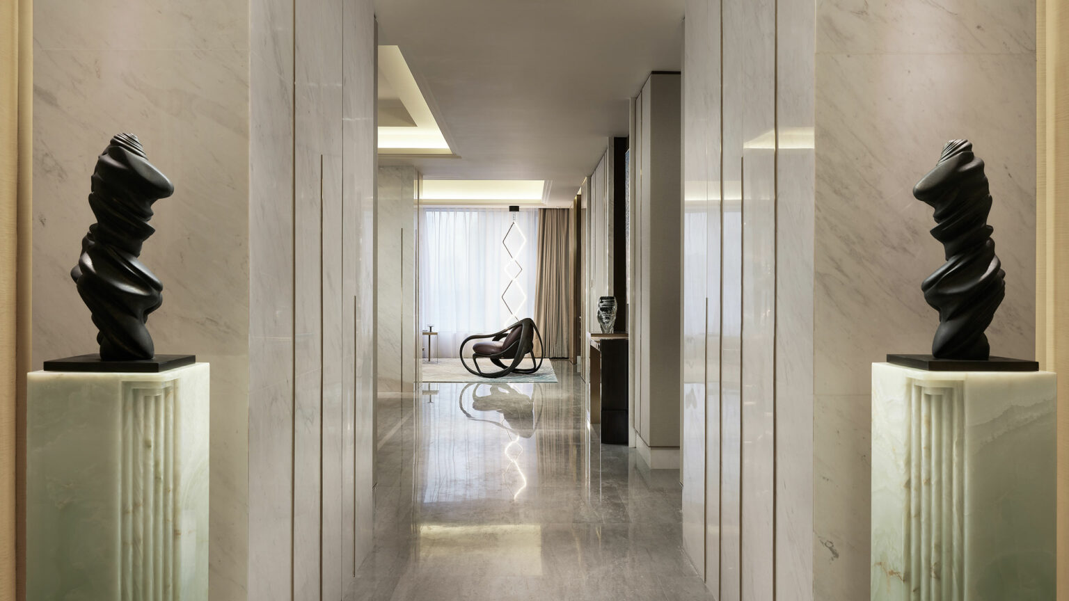 A modern hallway with sleek marble walls and floors, featuring abstract black sculptures on pedestals. Sunlight filters through curtains, creating a calm ambiance.