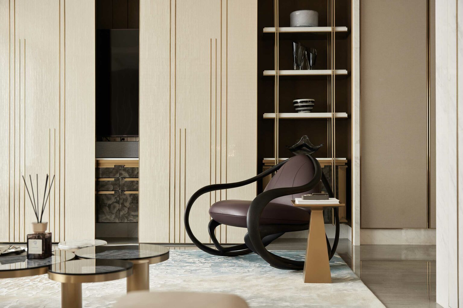 A modern living room features a sleek, dark wood rocking chair with purple cushions, a glass coffee table, and a geometric side table. Neutral tones create a calm ambiance.