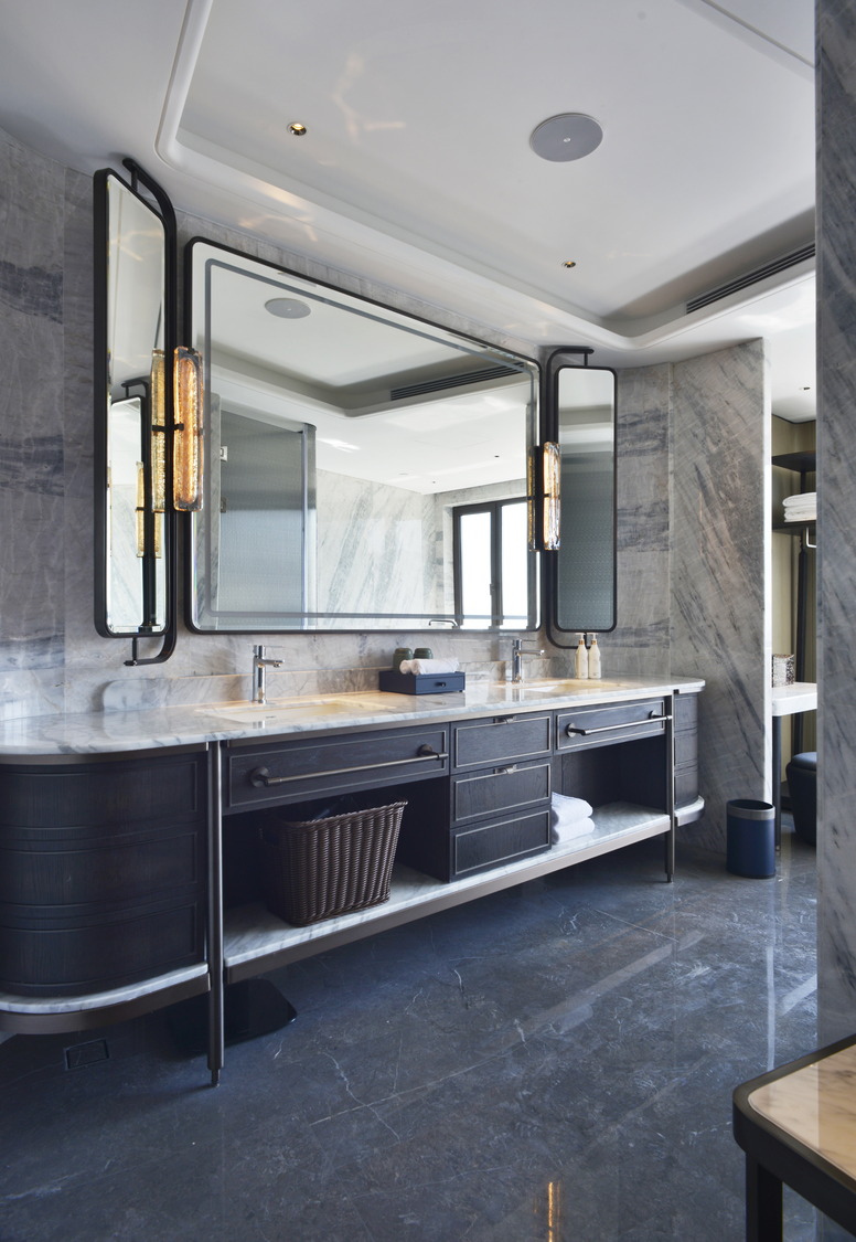 Modern hotel room with two beds, sleek gray tones, and elegant lighting. Features include a seating area, TV, and minibar, creating a cozy yet sophisticated ambiance.