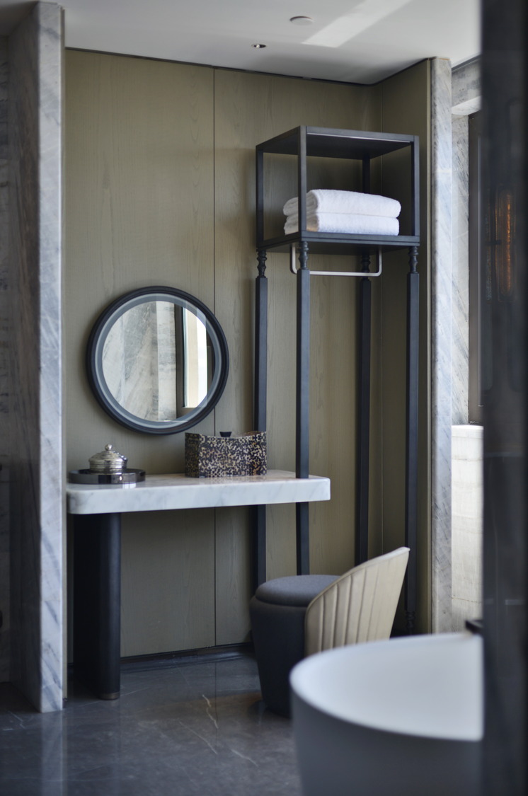 Modern hotel room with two beds, sleek gray tones, and elegant lighting. Features include a seating area, TV, and minibar, creating a cozy yet sophisticated ambiance.
