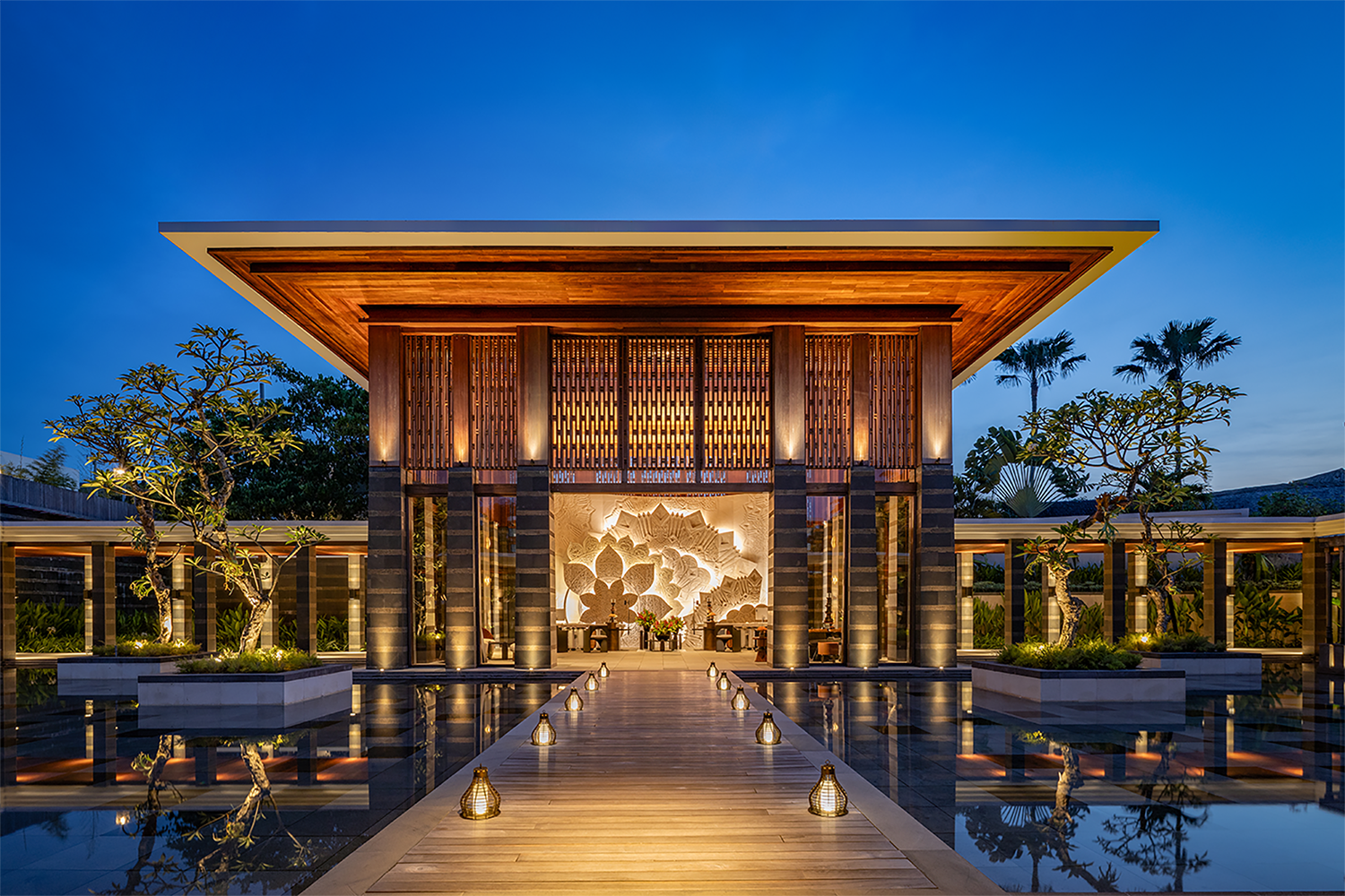 Experience luxury and serenity at this stunning modern resort entrance, featuring elegant wooden architecture, serene water reflections, and enchanting evening lighting.