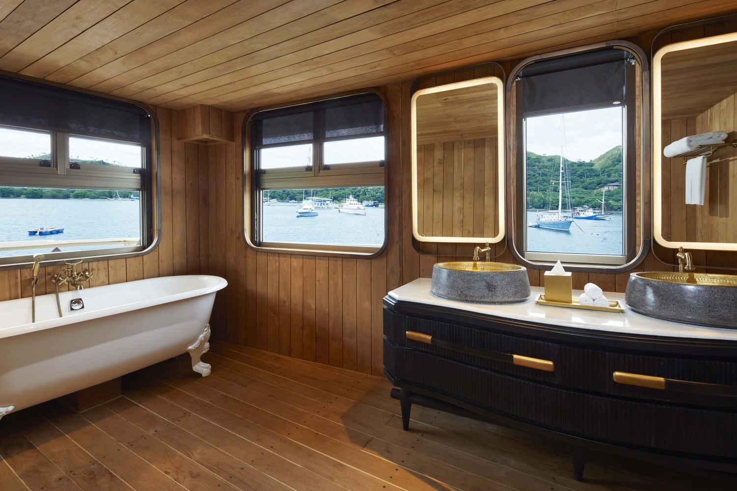 Luxurious yacht cabin with a king-sized bed, white linens, and a vibrant blue abstract headboard. Soft lighting and modern decor create a serene atmosphere.