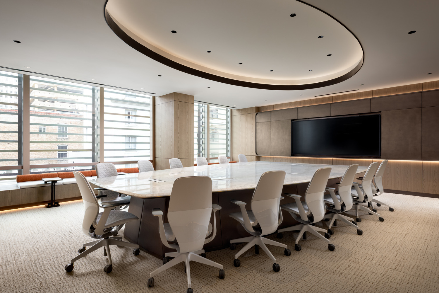 Sophisticated modern office lounge with beige decor, plush seating, and a sleek glass fireplace. Floor-to-ceiling windows and greenery create an airy, relaxing atmosphere.