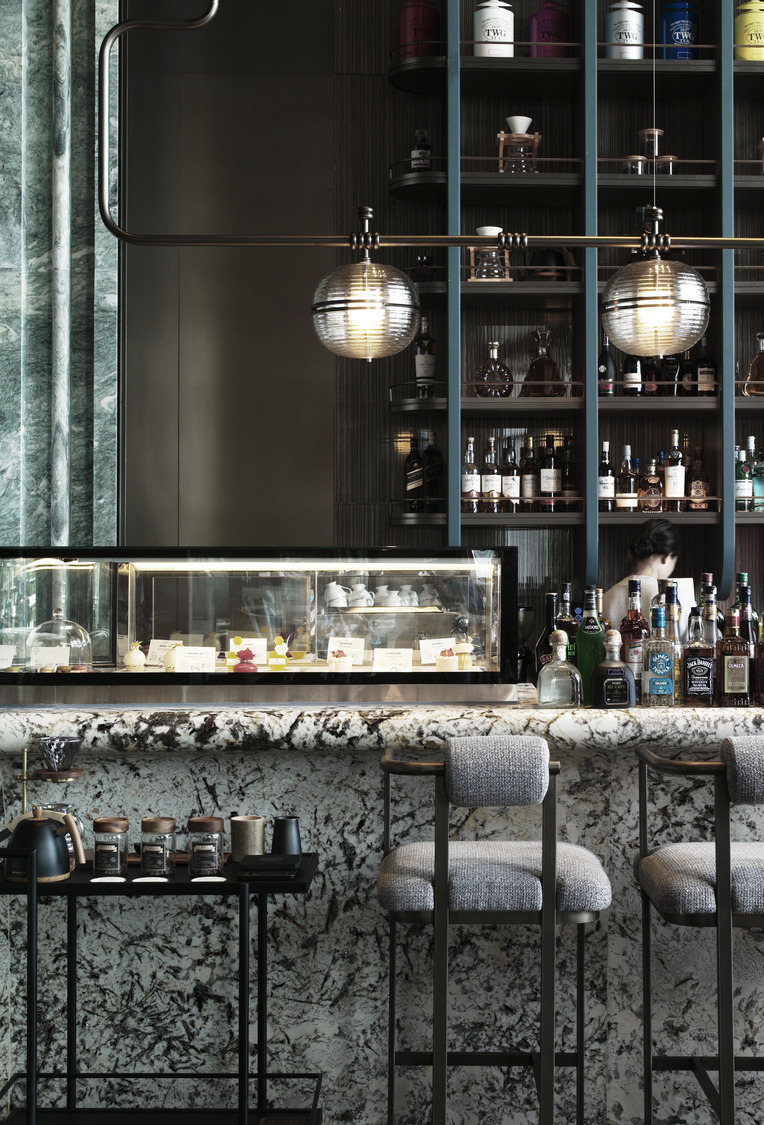 Luxurious hotel lounge with modern decor, featuring a wavy teal wall, linear fireplace, round seating, ambient lighting, and a leafy green plant.