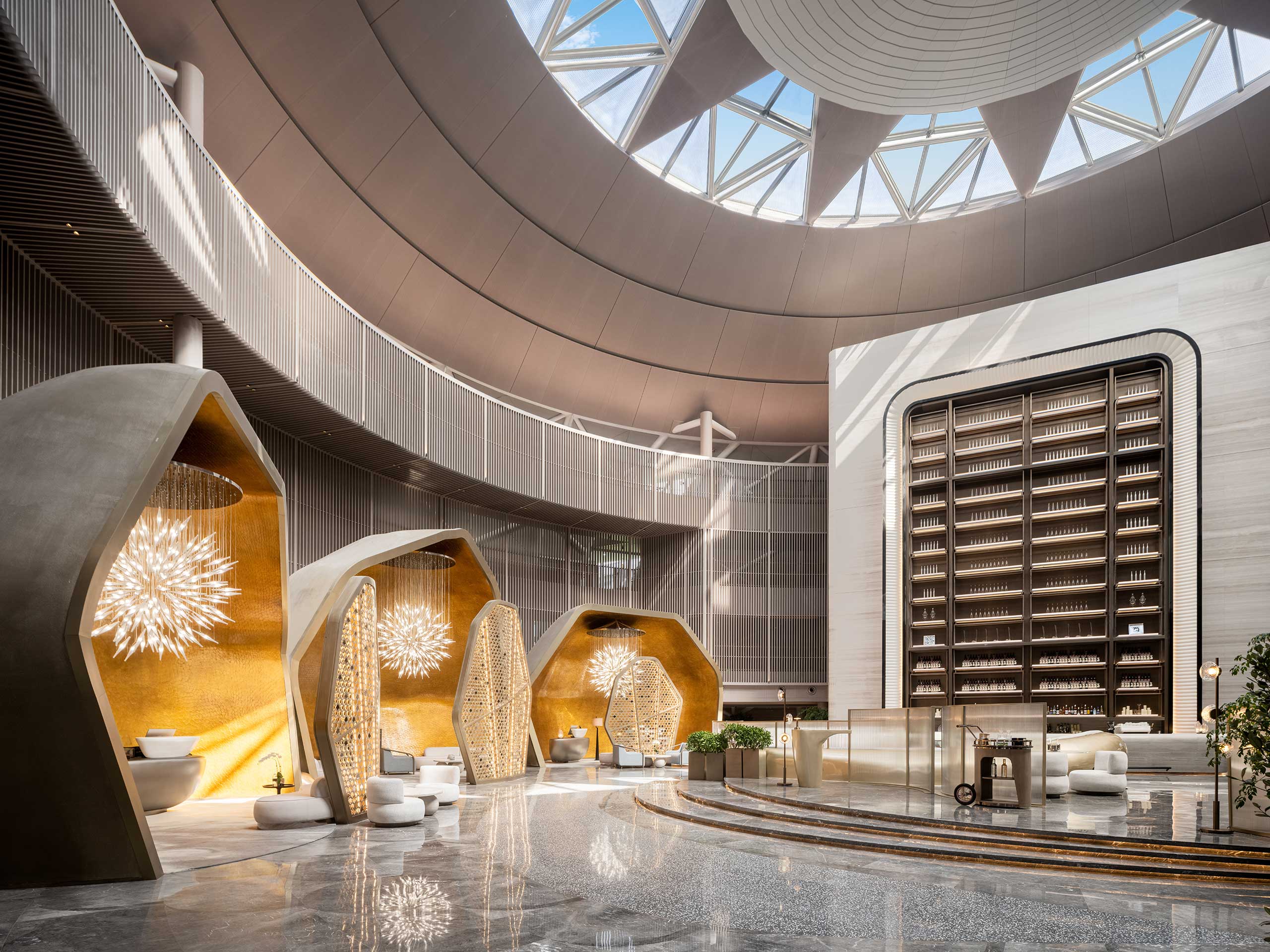 Modern hotel spa atrium with geometric features, a domed glass ceiling, large bookcase, and illuminated seating pods. Bright, spacious, and elegant atmosphere.