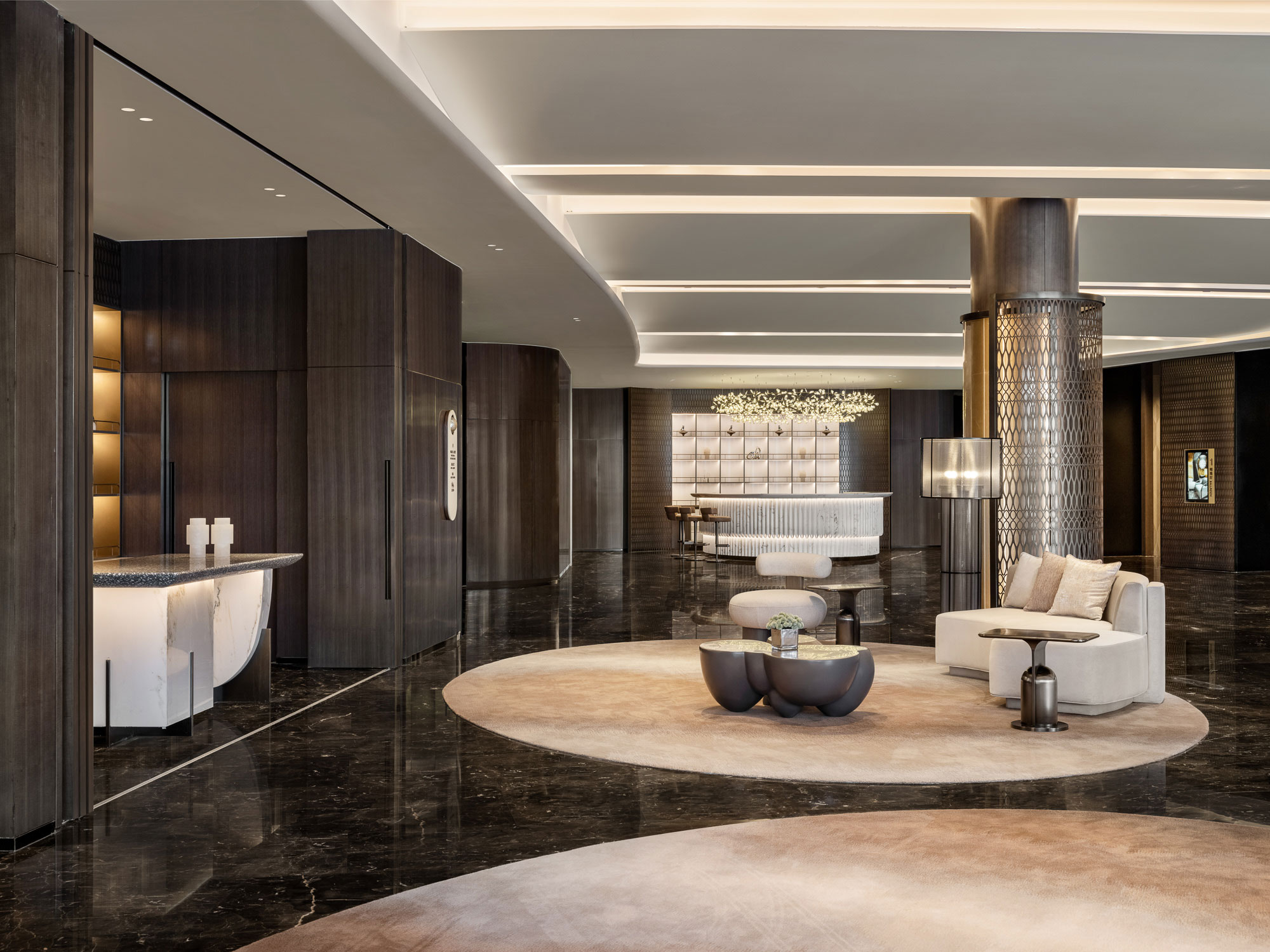 Modern hotel lobby featuring sleek, dark wood accents and marble floor. Elegant seating with neutral tones creates a sophisticated, welcoming ambiance.