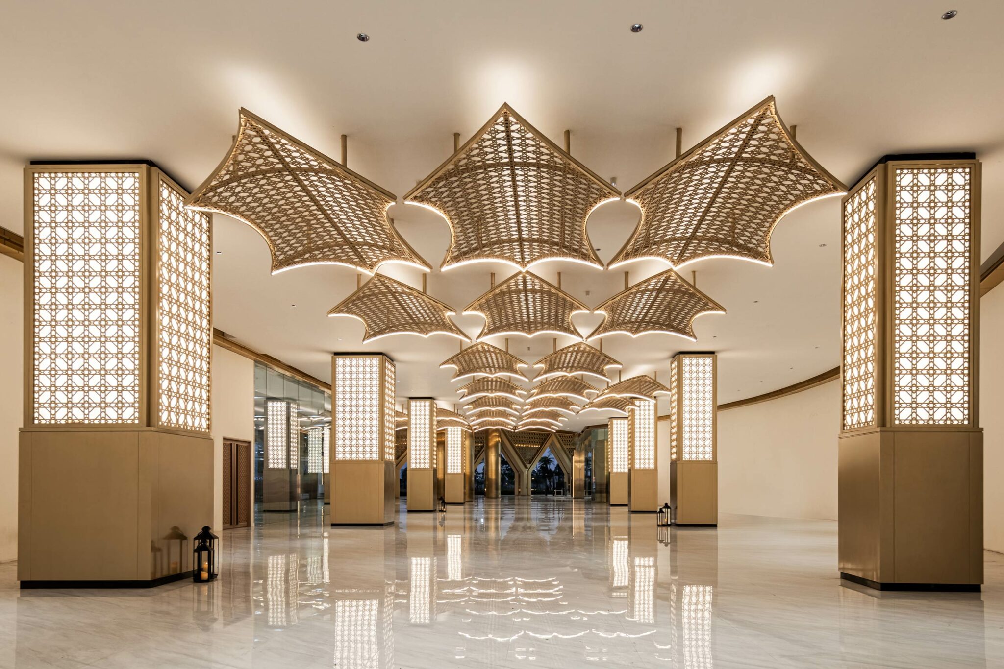 Luxurious office lobby with ornate, fan-shaped ceiling lights and glowing patterned columns on glossy marble flooring, creating an elegant ambiance.