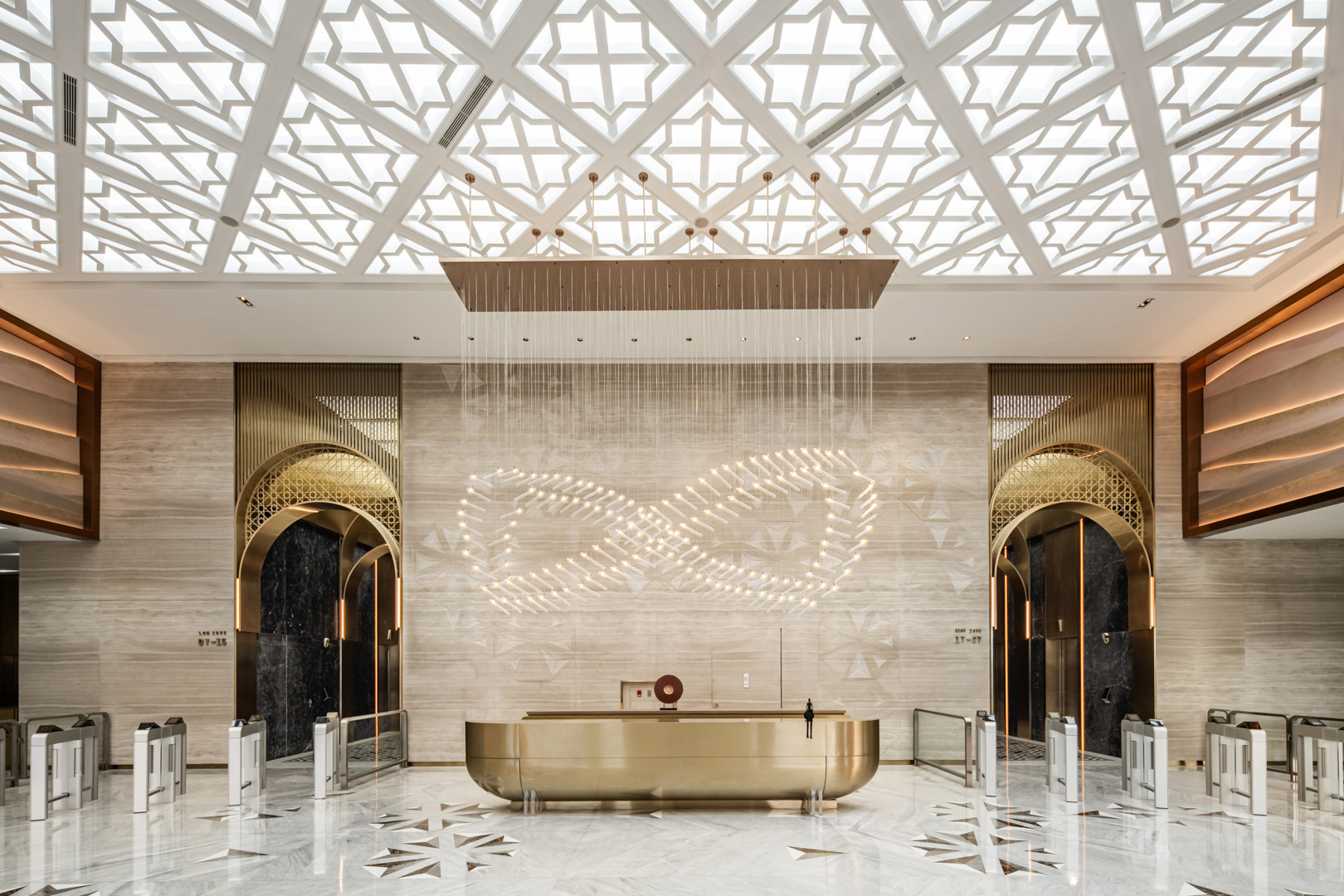 Luxurious office lobby with a golden reception desk. A patterned ceiling and wave-like light fixture add an elegant, modern touch. Arched doorways with ornate designs flank the scene.