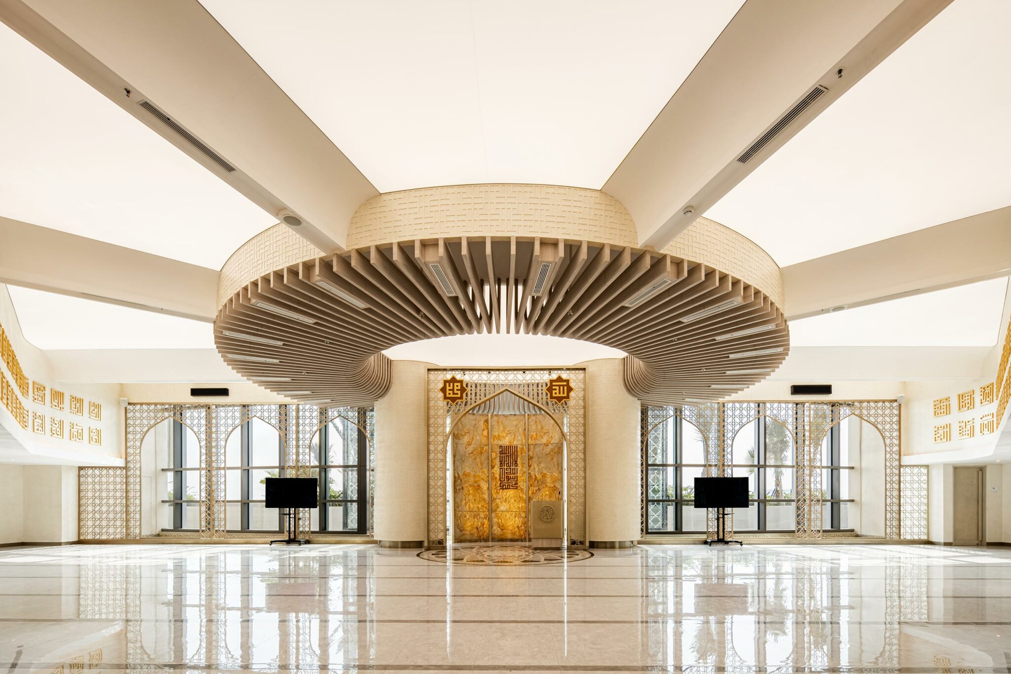 Modern interior of an office prayer hall with geometric designs, arched windows, and intricate ceiling centerpiece. The space feels serene and elegant.