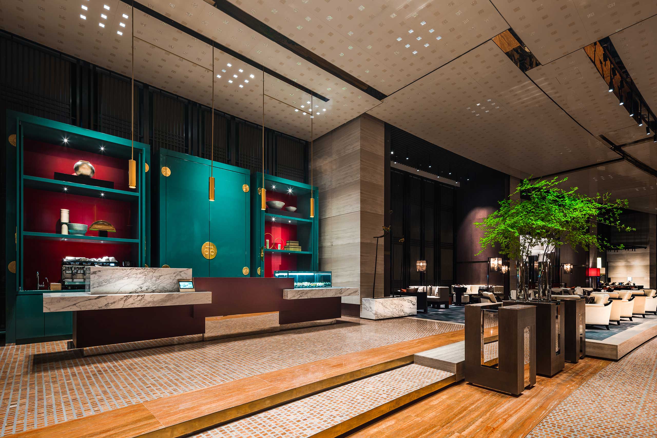 Modern hotel lobby with a sleek marble reception desk, vibrant teal and red shelving, elegant lighting, and a lush indoor tree. The space conveys luxury.