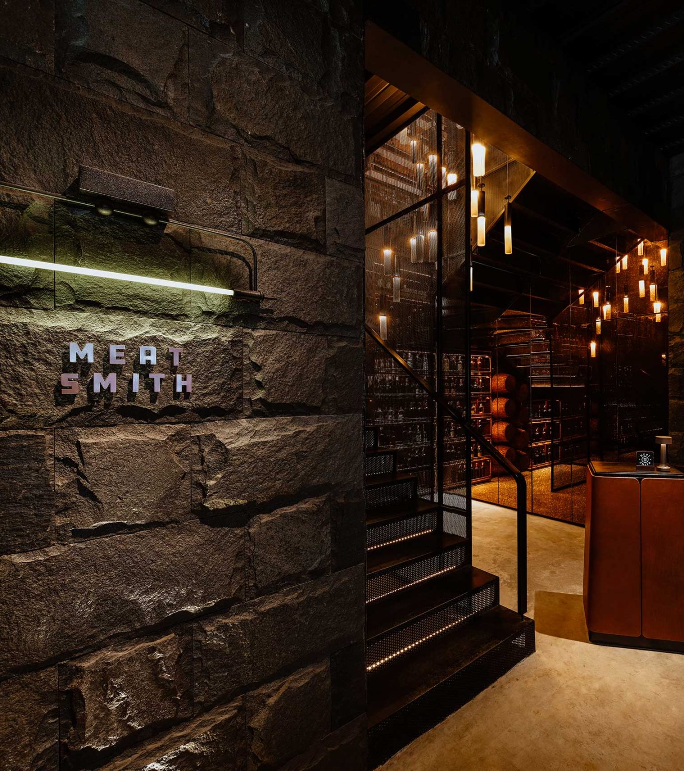 Dimly lit charcuterie area of a restaurant with stone walls, a sign reading