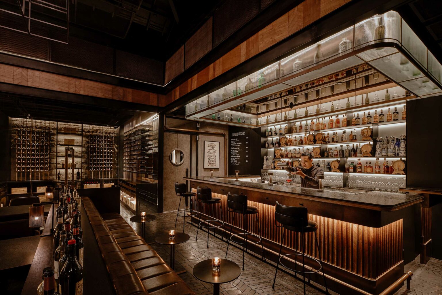 Sophisticated restaurant bar with dim lighting, featuring shelves of liquor bottles, a bartender mixing a drink, leather stools, and a cozy, elegant ambiance.