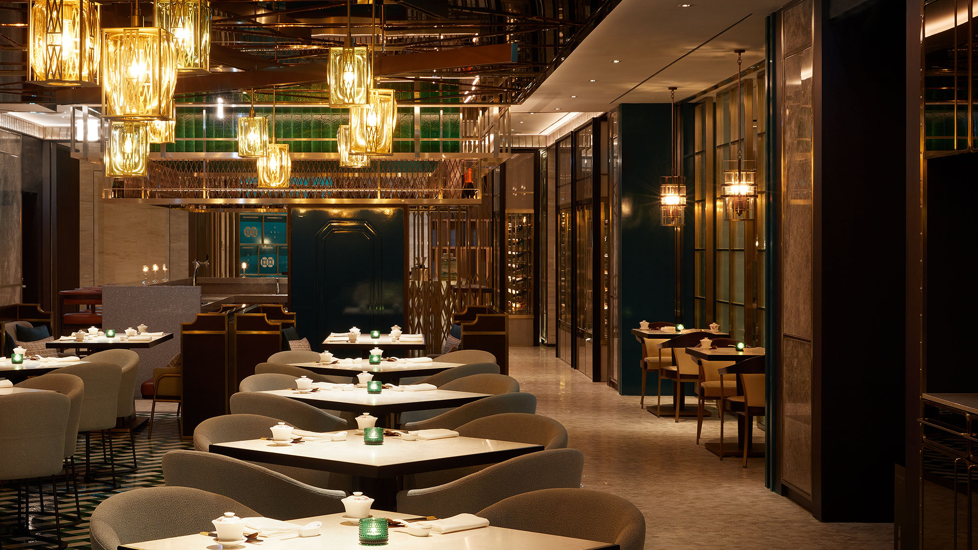 Elegant hotel restaurant interior with warm lighting features modern, geometric chandeliers and cozy beige seating. Sophisticated and inviting ambiance.