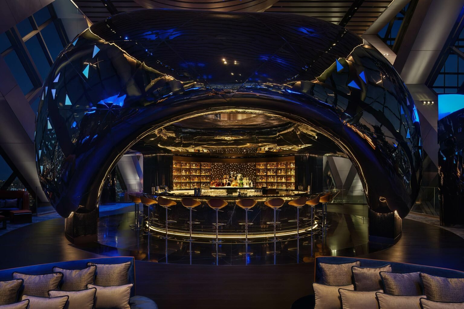 A sleek, futuristic bar with a glossy dome ceiling, warmly lit interior, and elegant bar stools. The ambiance is luxurious and inviting with a modern touch.