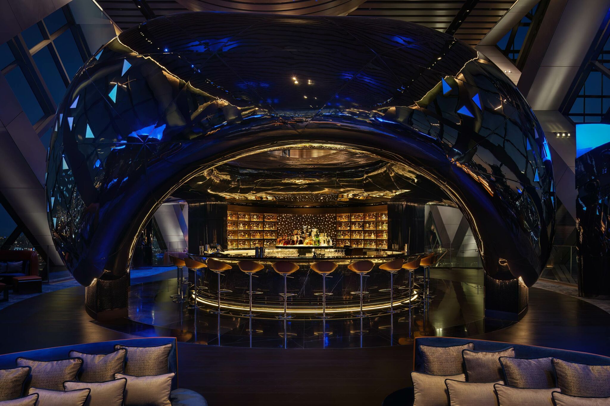 A sleek, futuristic bar with a glossy dome ceiling, warmly lit interior, and elegant bar stools. The ambiance is luxurious and inviting with a modern touch.