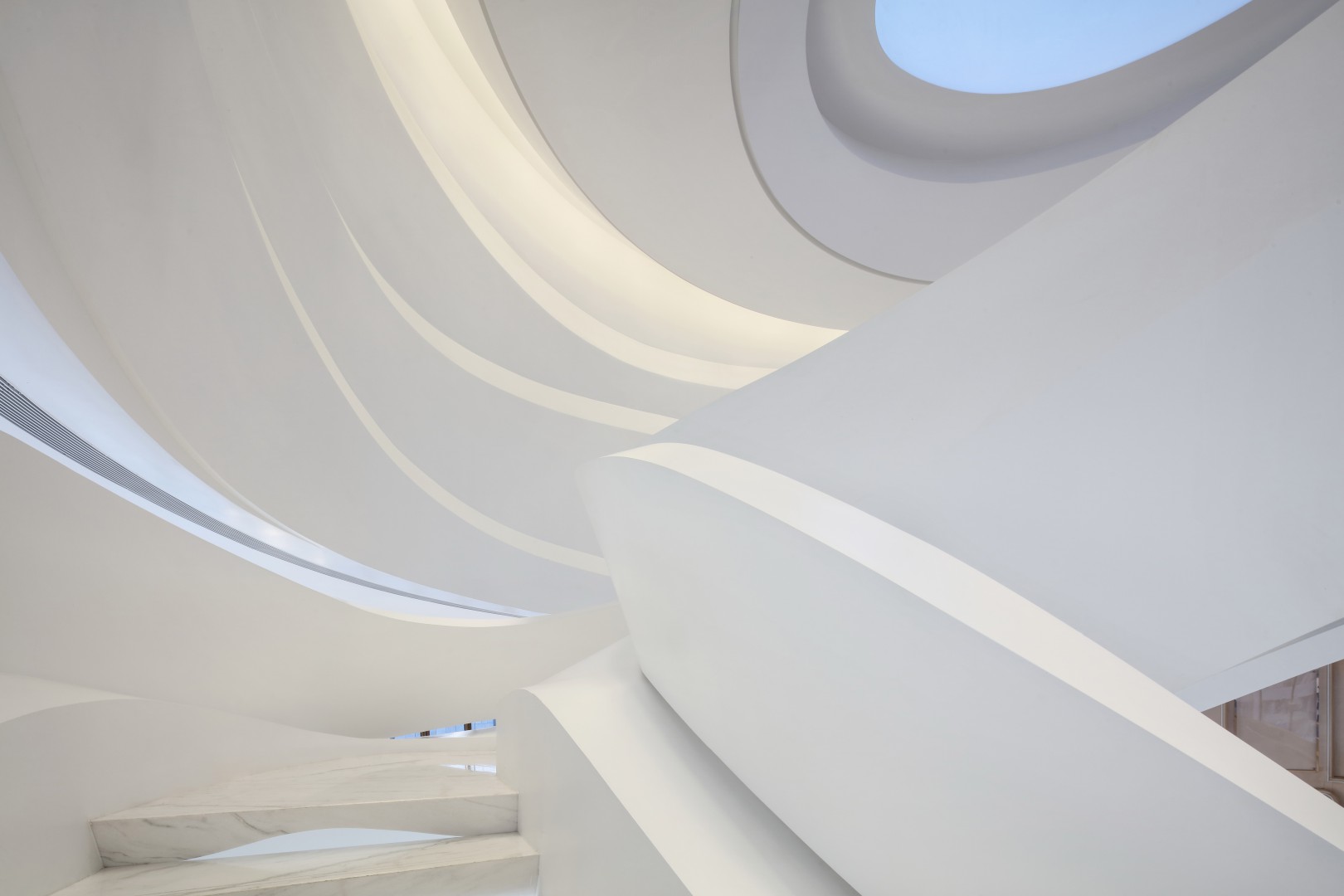 Curved white architectural structures with sleek lines and soft lighting create a serene and futuristic ambiance. The ceiling features an oval opening.