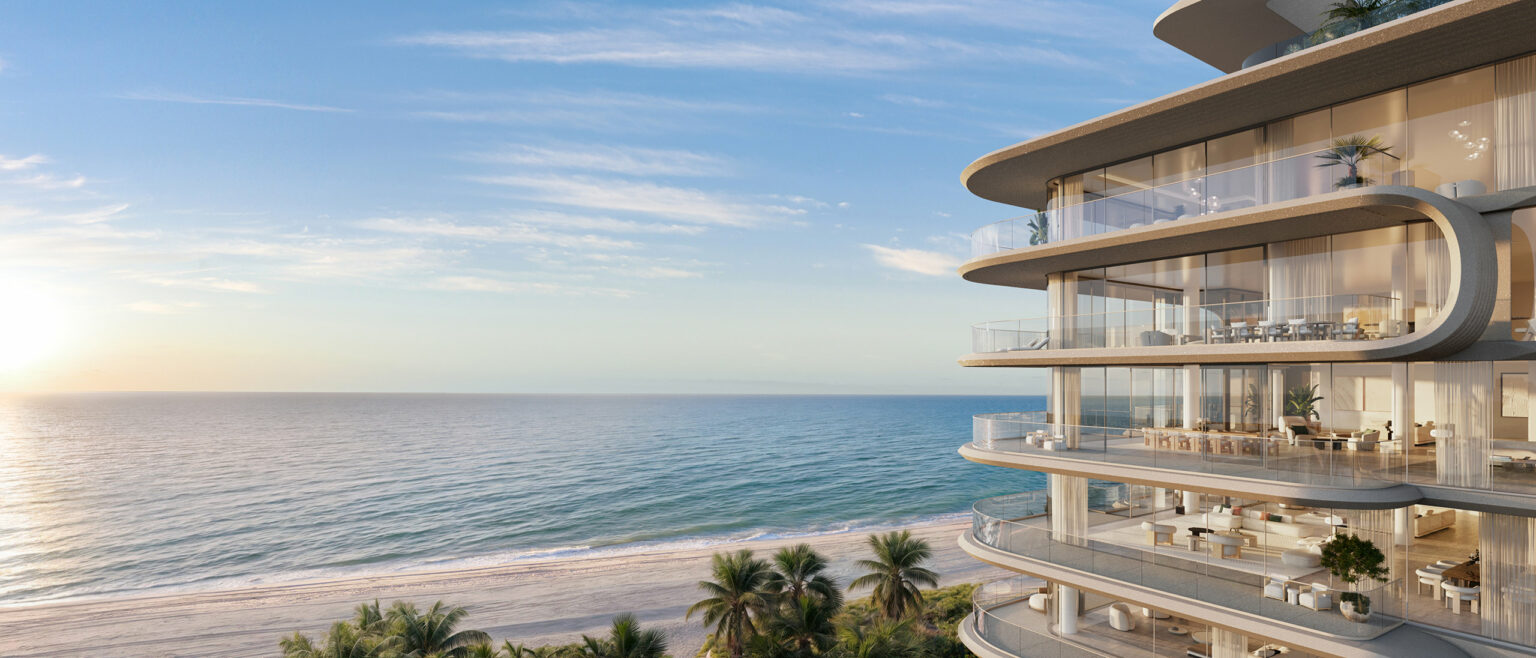 Luxury seaside condominium with glass balconies overlooking a serene ocean and sandy beach. Palm trees dot the coastline under a clear blue sky.