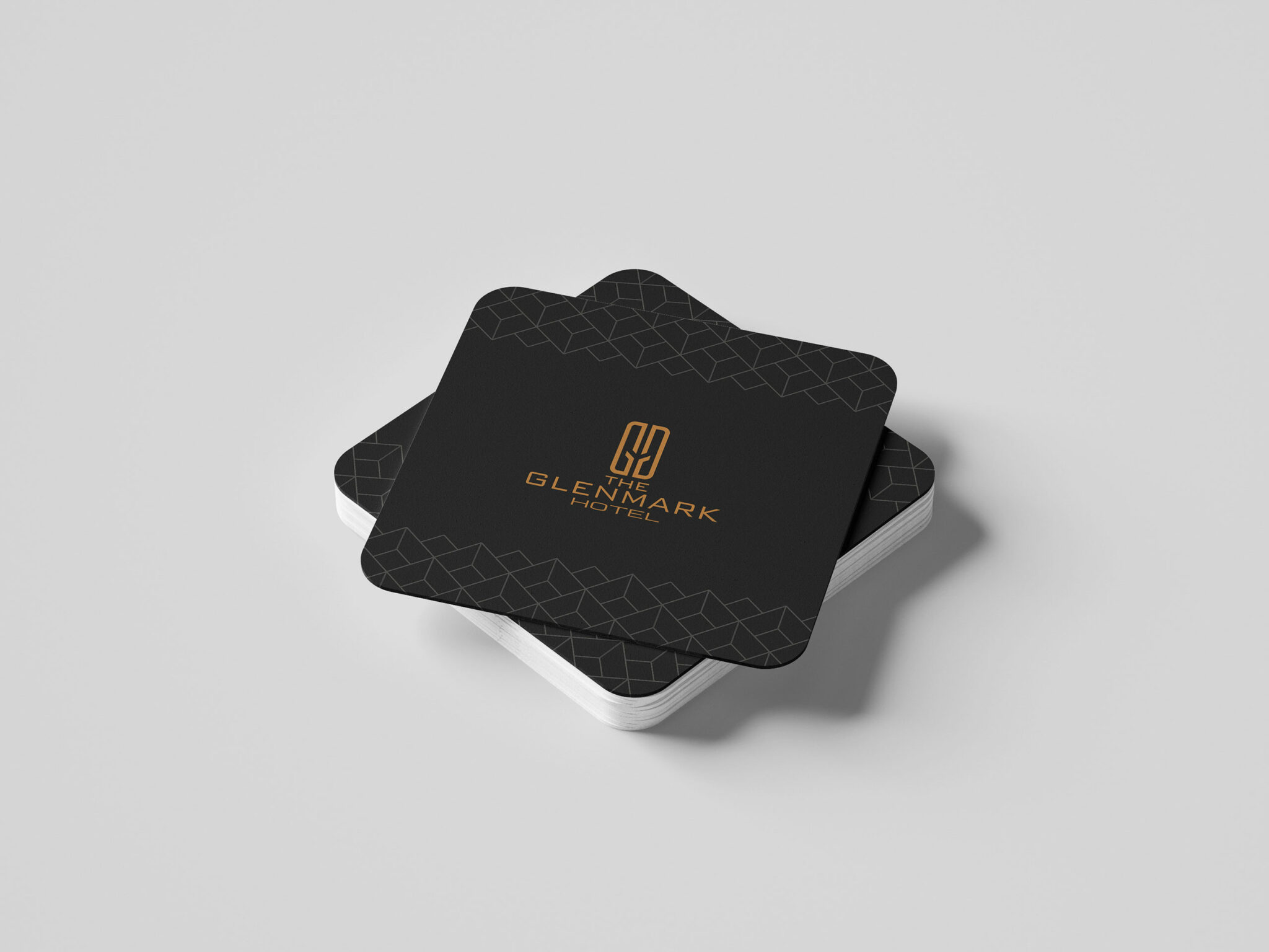 The Glenmark Hotel branding collateral featuring a stack of black drink coasters with elegant geometric patterns with 