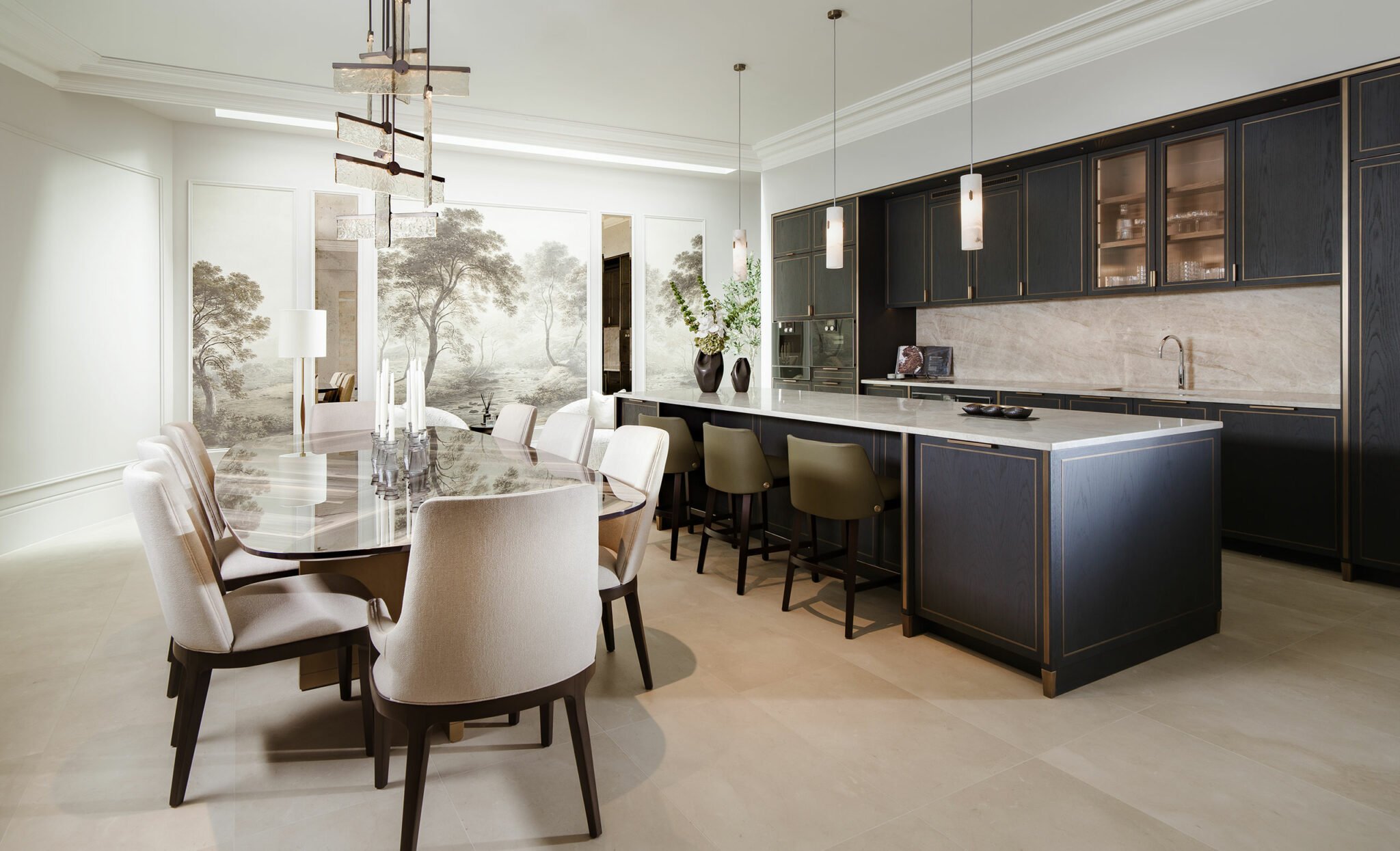 Luxurious kitchen and dining area with elegant light fixtures, plush chairs, dark cabinetry, and nature-themed wall art, creating a sophisticated ambiance.
