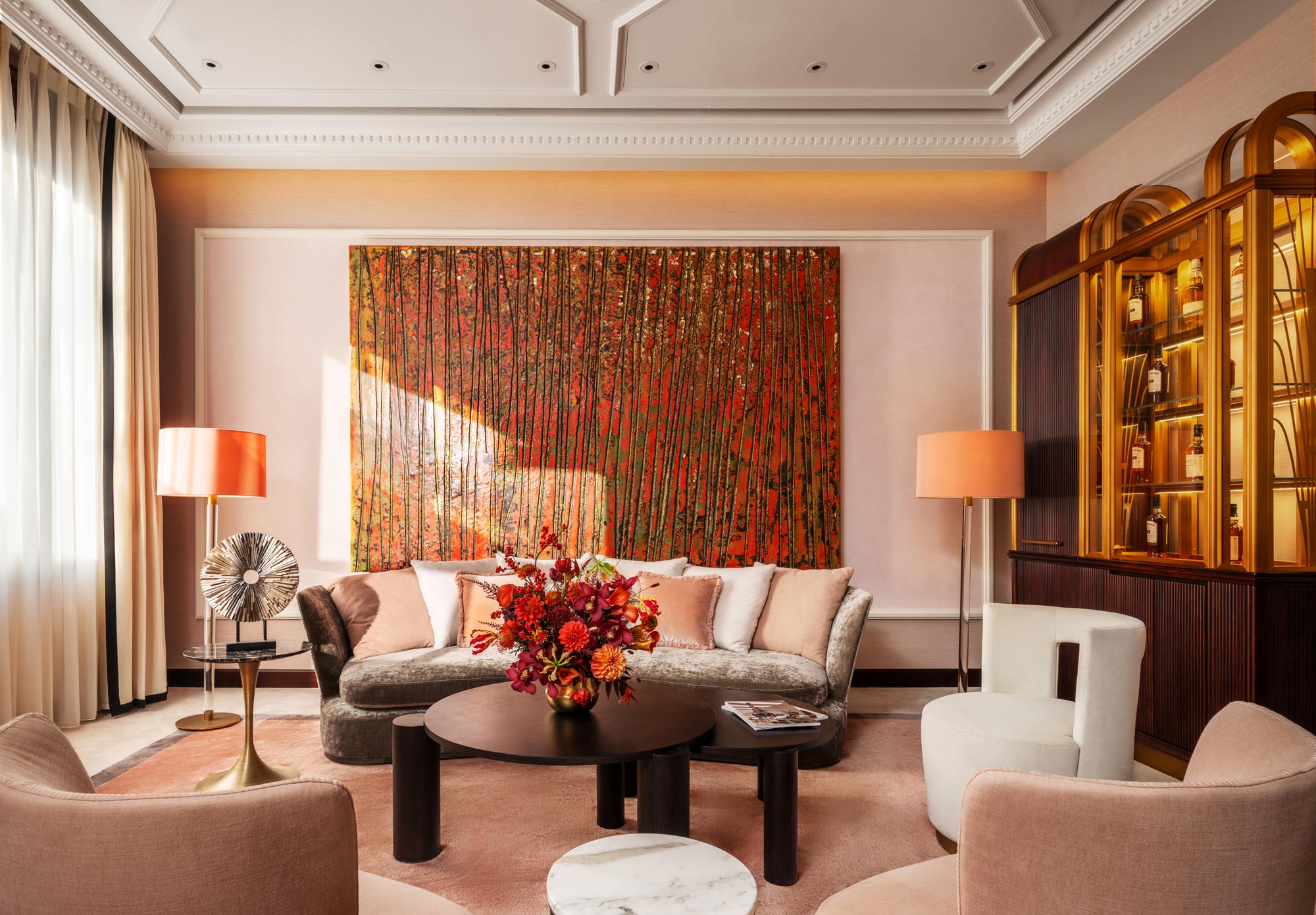 Elegant private club private room with a vibrant abstract painting above a plush sofa. Warm tones, chic decor, and soft lighting create a cozy, inviting atmosphere.