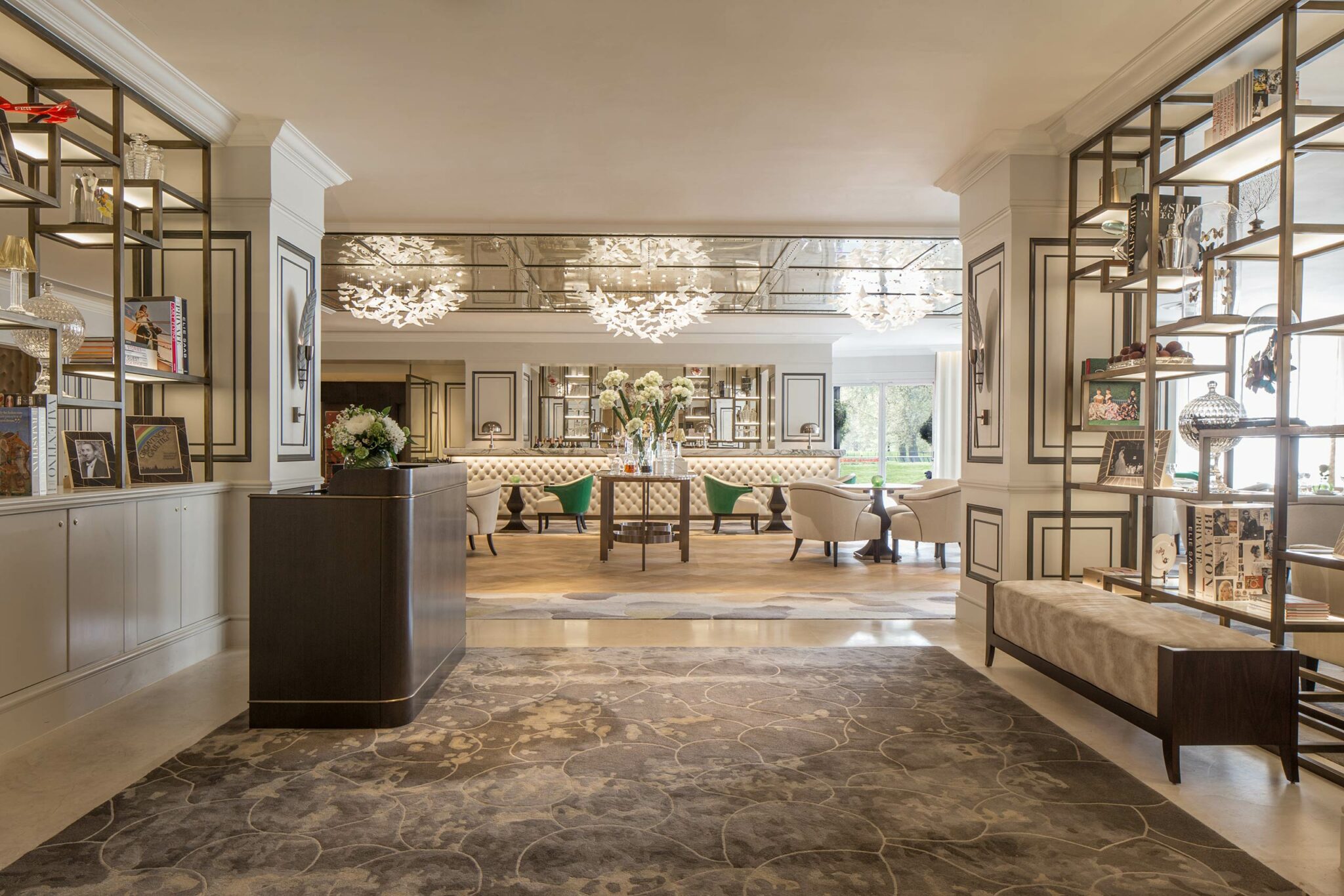 Elegant hotel lobby with plush seating, decorative shelves, and artful lighting. Neutral tones create a luxurious, welcoming atmosphere.