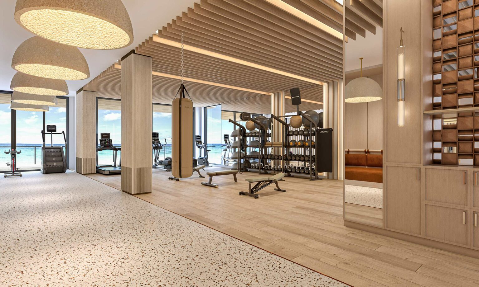 Modern home gym interior with wooden accents, featuring treadmills, exercise equipment, a punching bag, and ocean views through large windows, conveying a calm, spacious atmosphere.