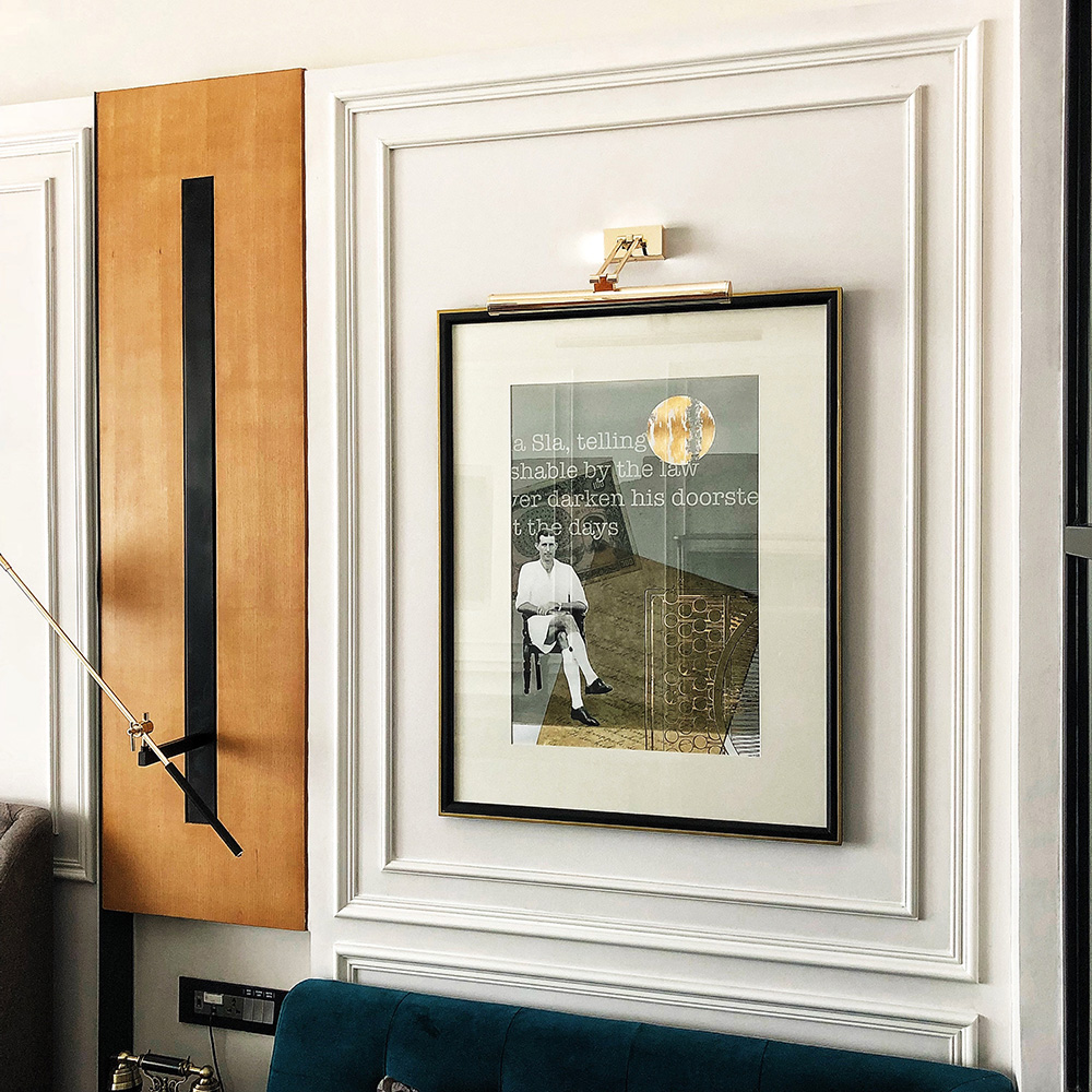 Framed artwork on white wall featuring an image of a person seated with abstract elements and text. Warm lighting creates a modern, sophisticated mood.