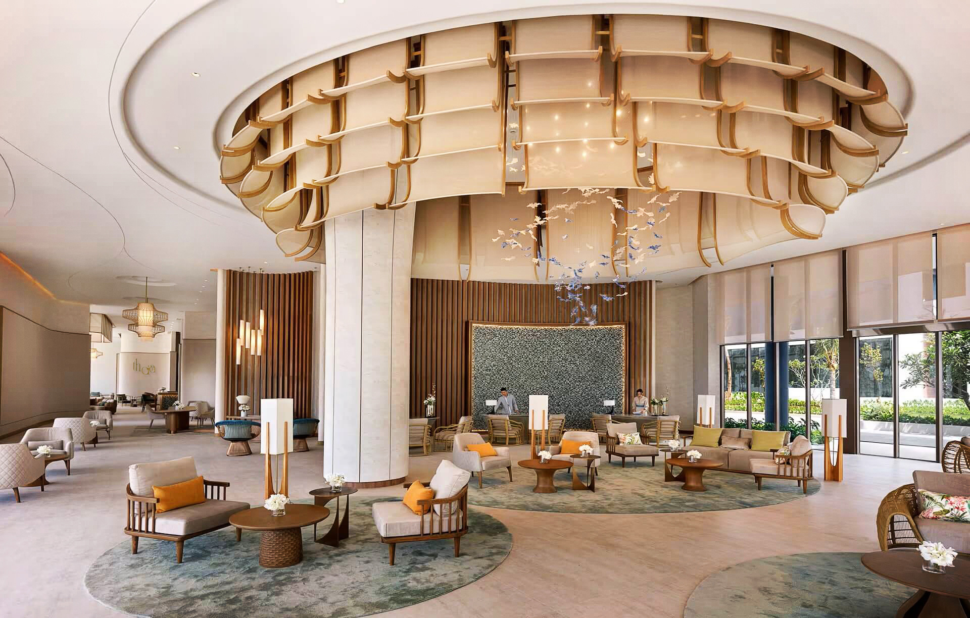 Spacious, elegant hotel lobby with modern decor. Features a large, intricate ceiling design, plush seating, soft lighting, and a serene, inviting ambiance.