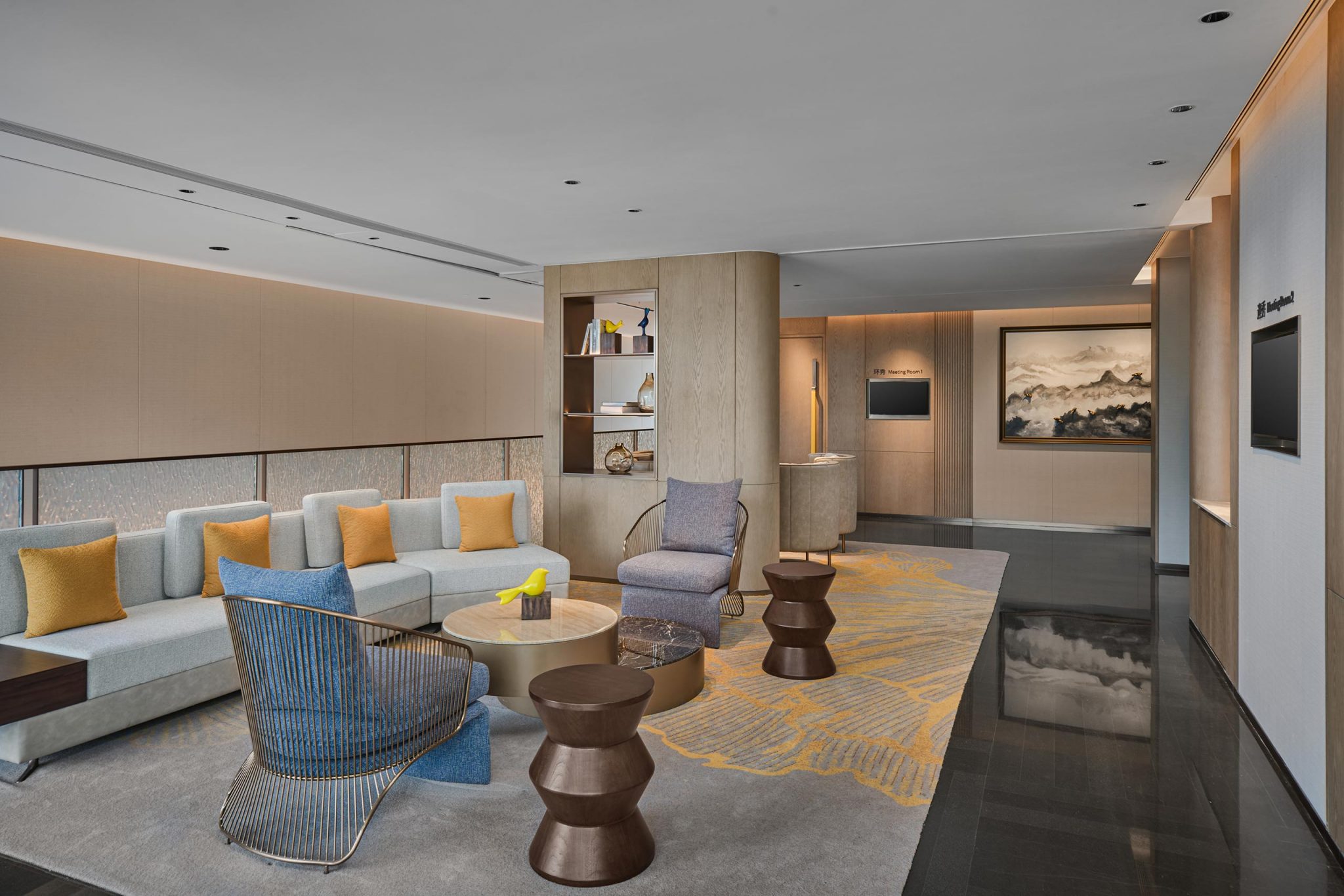 Modern living room with neutral tones, featuring a beige sectional sofa with yellow cushions, a round coffee table, abstract art, and sleek decor.