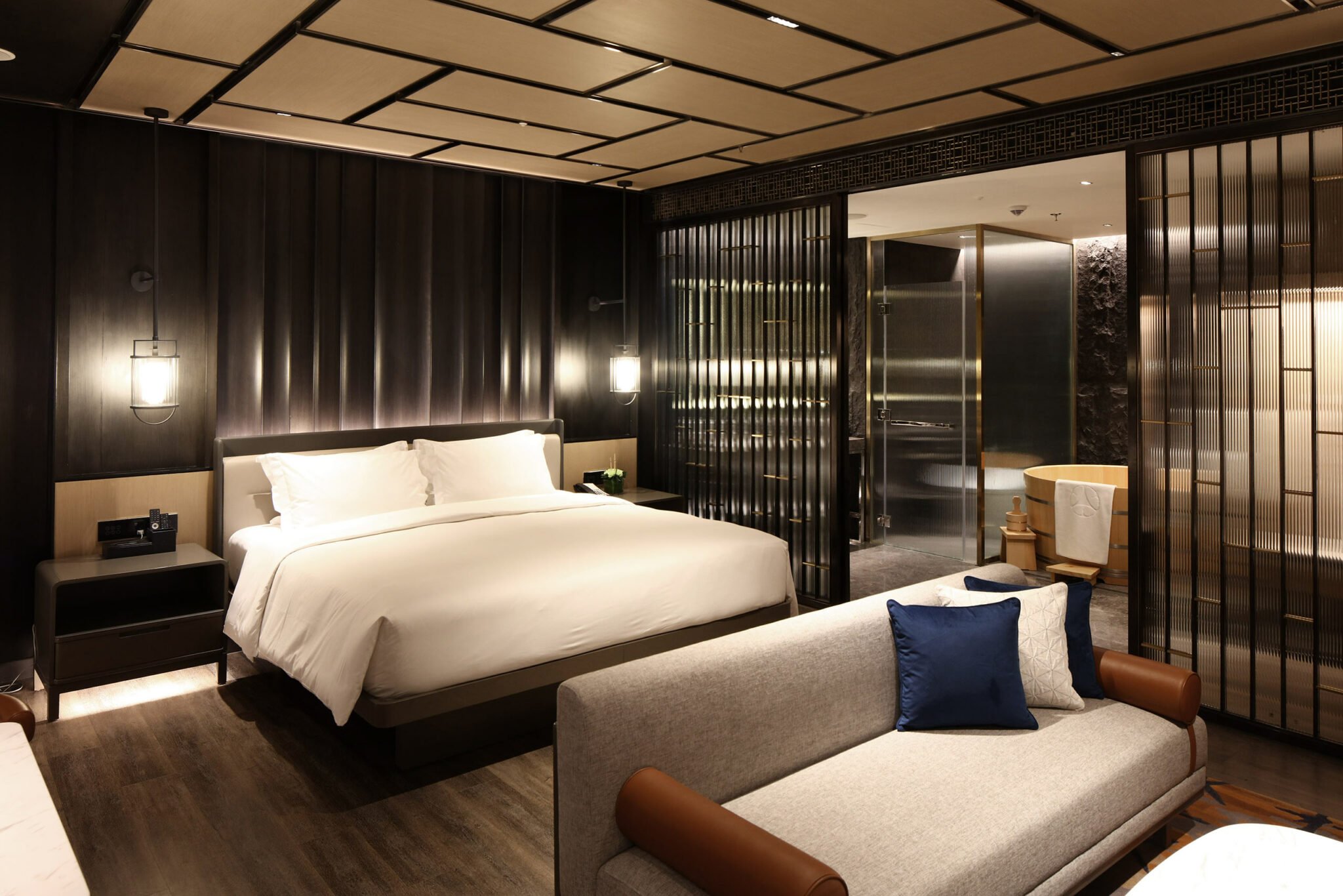 Elegant hotel room with a king-size bed, soft lighting, and contemporary design. Features a modern partitioned bathroom and cozy seating area.